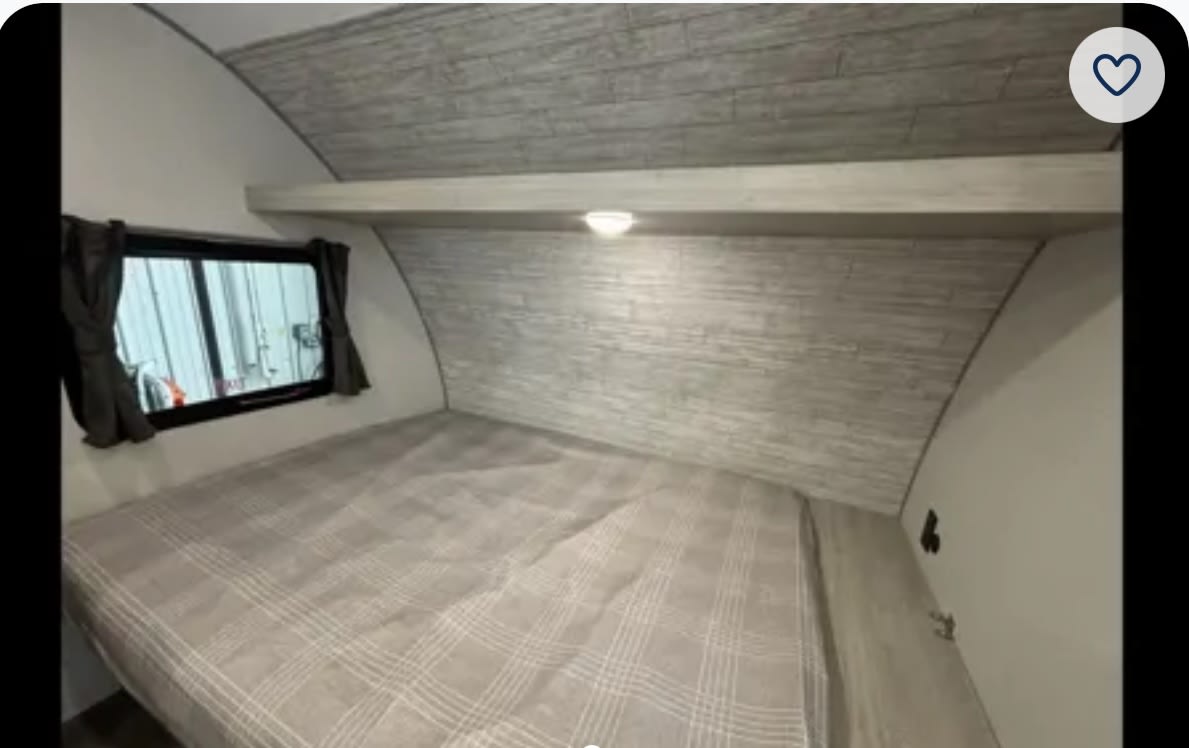 Cozy RV rental bedroom featuring a comfortable bed with plaid bedding, window, and overhead light, ideal for travel.. Forest River Coachmen Catalina Summit 2024