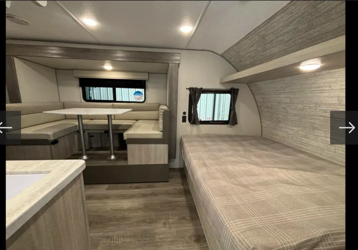 Spacious rv rental interior featuring a U-shaped dinette on the left and a comfortable bed on the right.. Forest River Coachmen Catalina Summit 2024