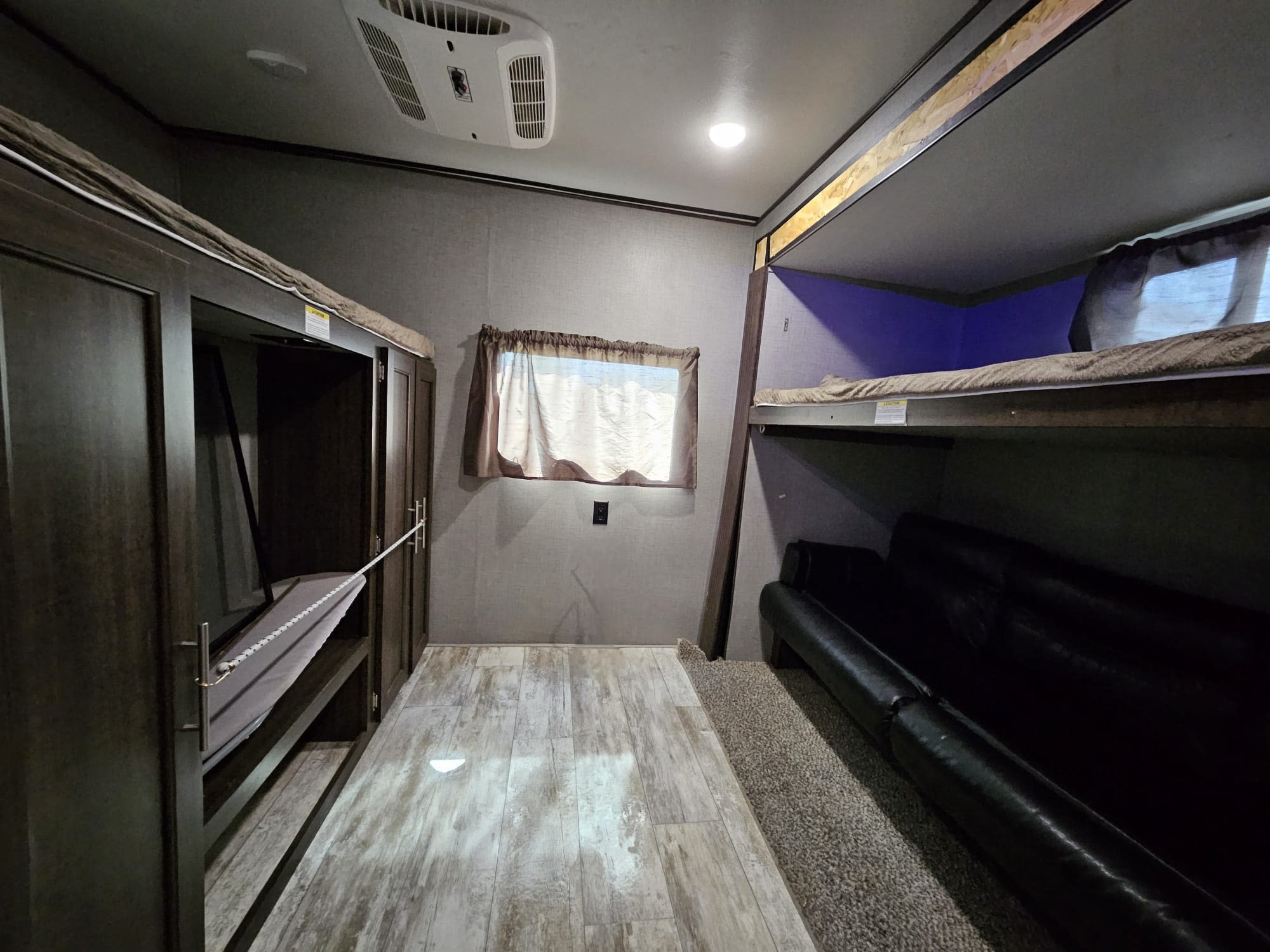 RV rental: Interior shows bunk beds with blue light, a second convertible bunk, and a black sofa for travelers.. Crossroads RV Zinger 2019