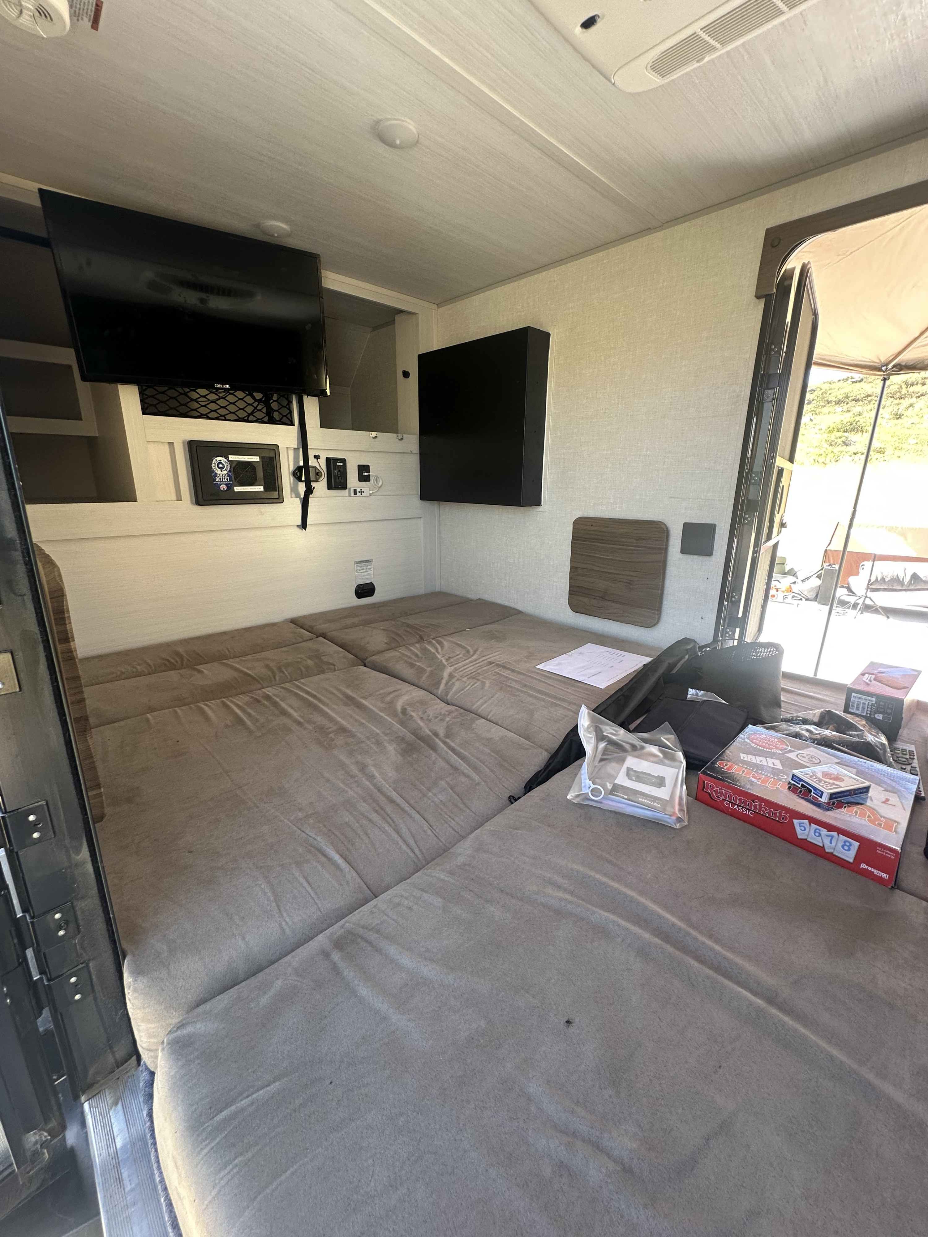 RV rental interior: This compact mobile space features a large sectional bed, wall-mounted TVs, and system controls for comfort.. Forest River Nobo 10.6 2023