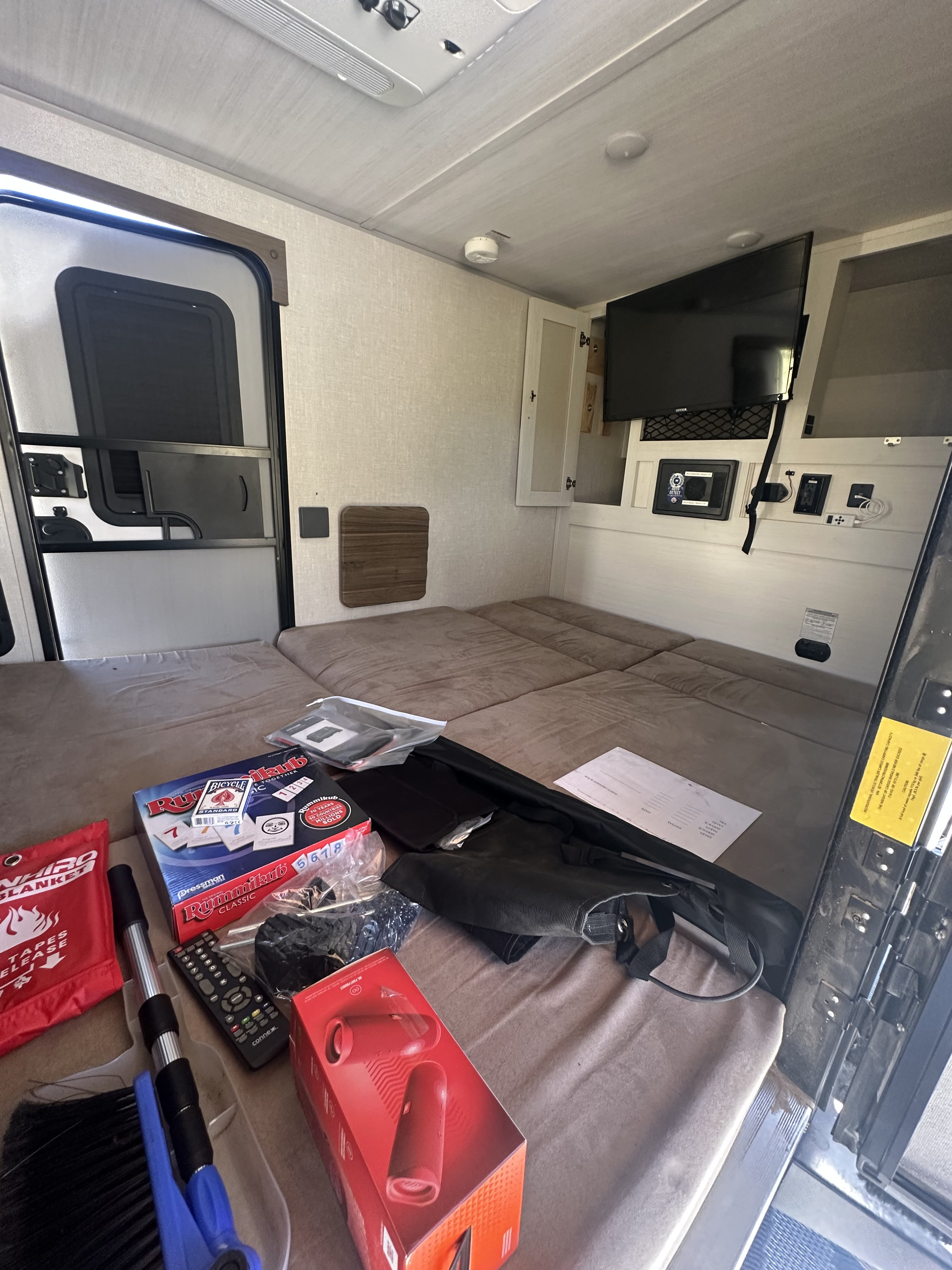 RV rental interior: a comfy bed, TV, and essentials like games for your journey.. Forest River Nobo 10.6 2023