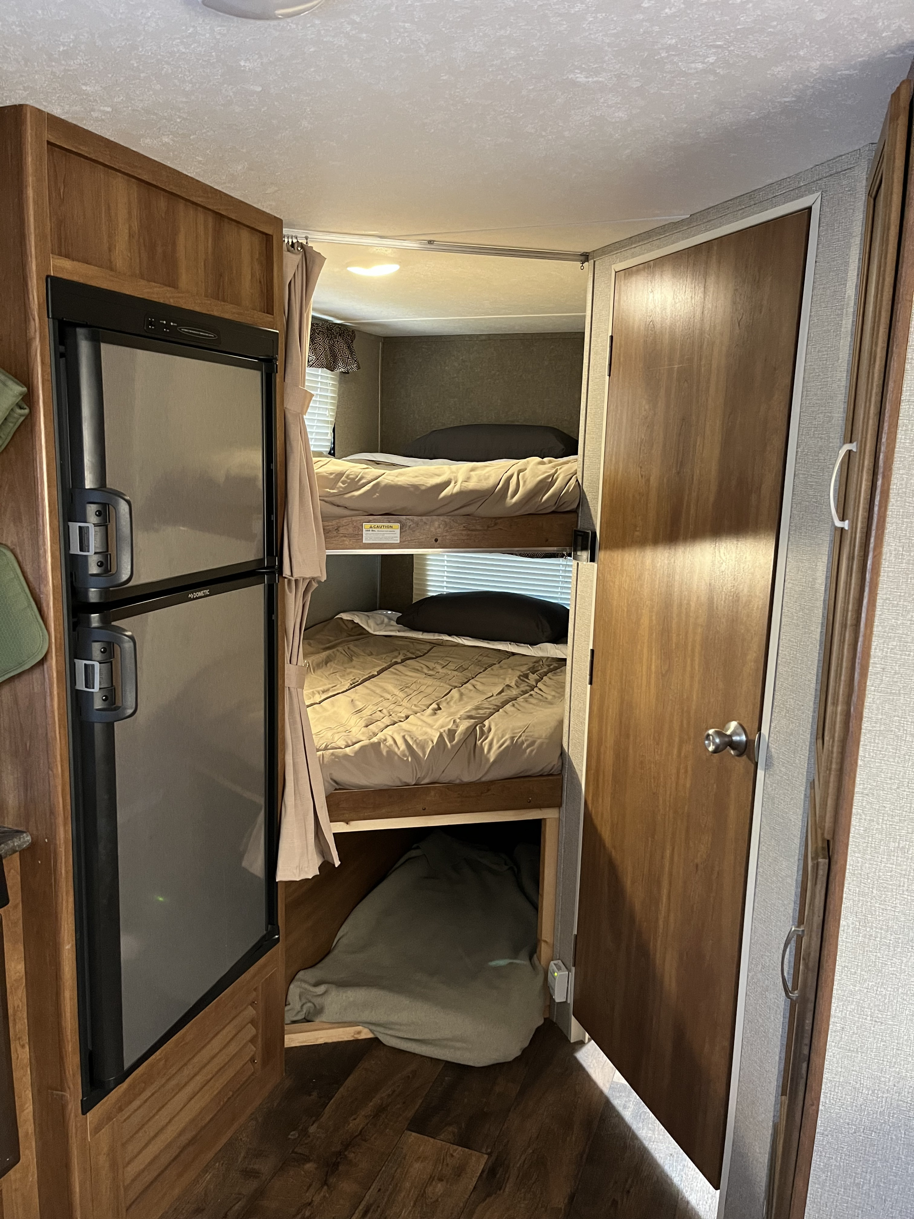 Cozy rv rental interior featuring double bunk beds and a refrigerator, ideal for comfortable family travel.. Keystone RV Springdale 2018