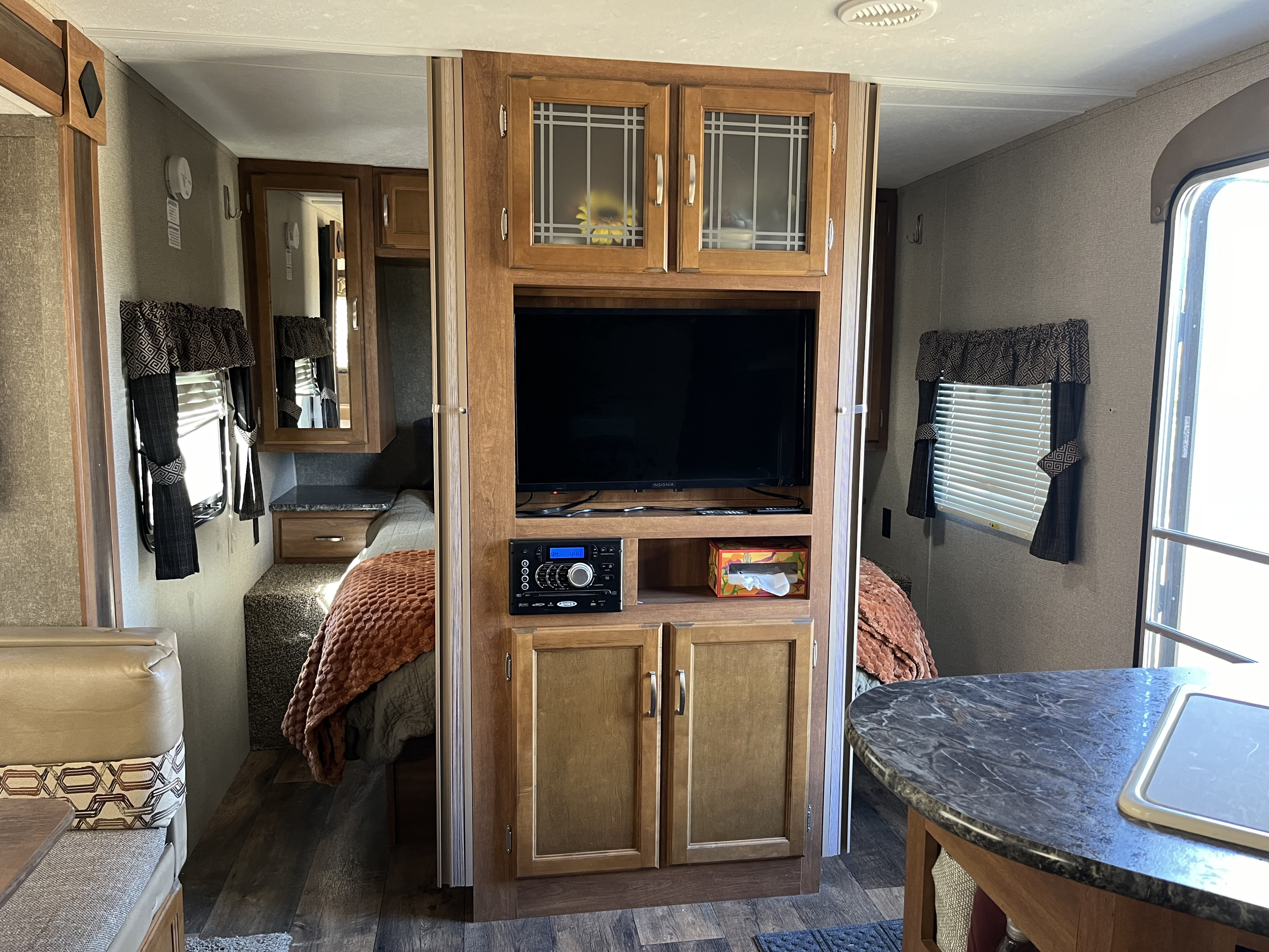 Inside an RV rental: cozy living space with TV and entertainment, partial bedroom, and kitchen counter for comfortable travel.. Keystone RV Springdale 2018