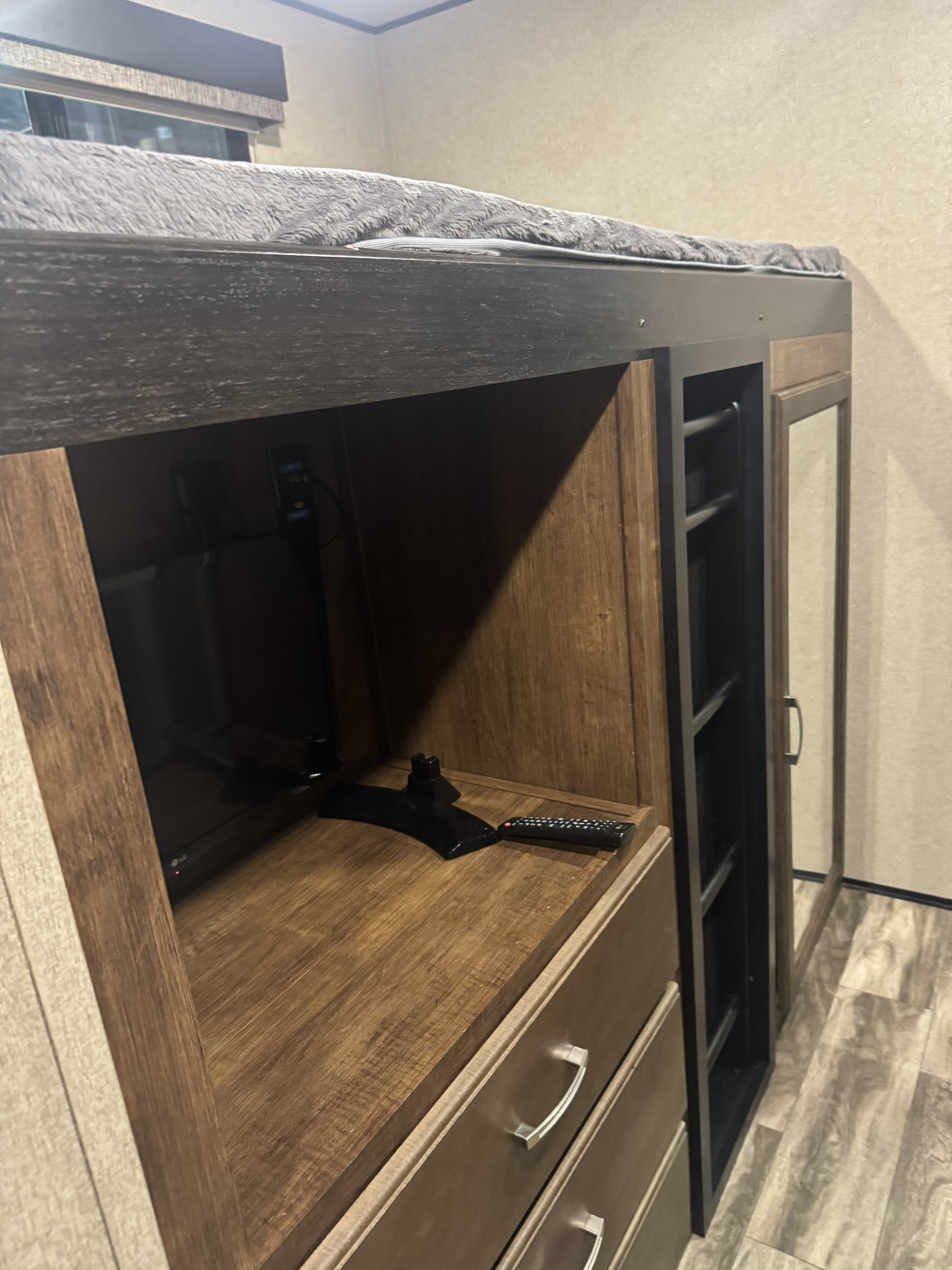 This RV rental's interior shows a bunk bed, built-in TV, drawers, and a narrow cabinet with glass door.. Grand Design Reflection 2020