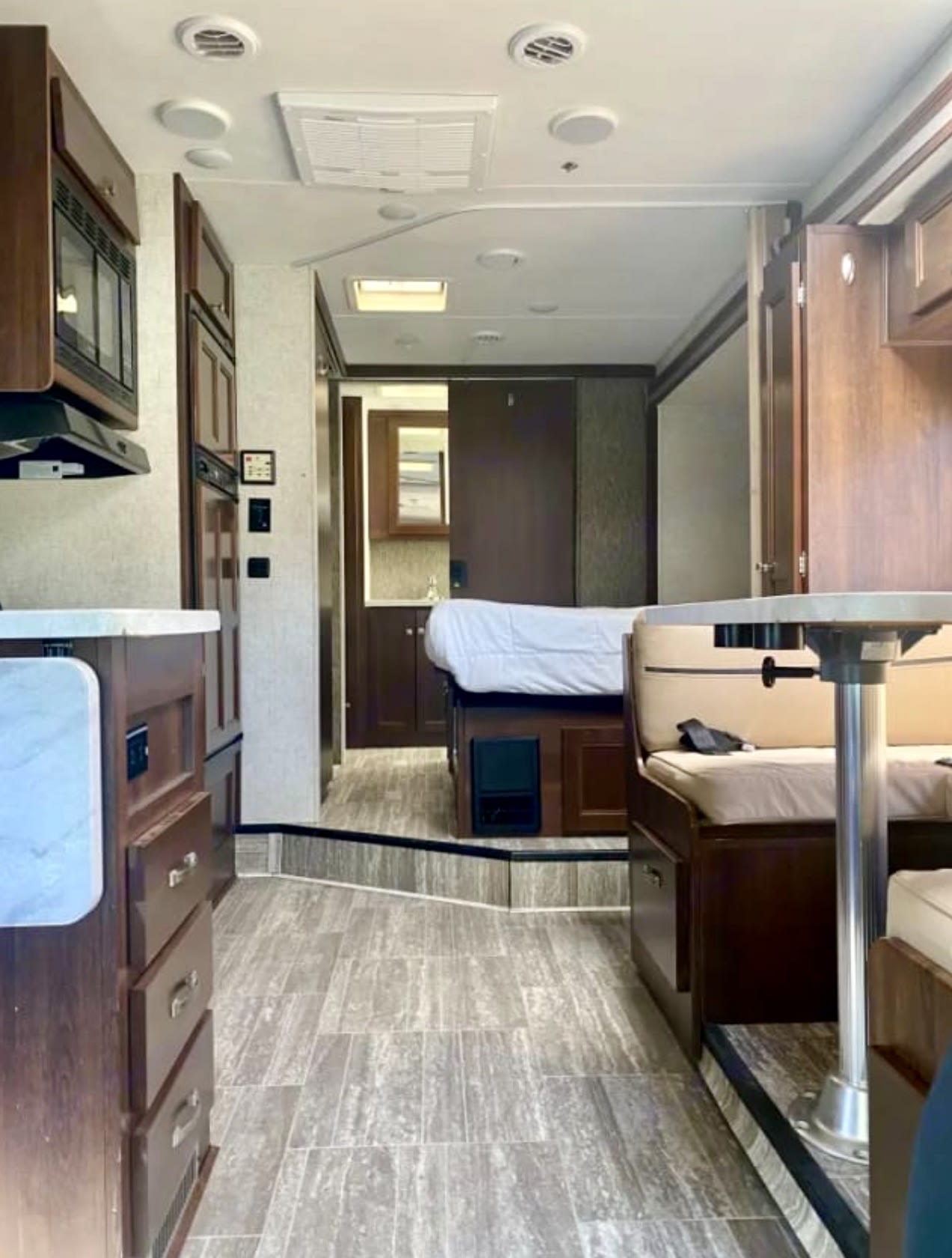 RV rental interior: kitchen, dinette, raised bedroom, and rear bathroom visible, showcasing compact and functional living.. Forest River Sunseeker 2018