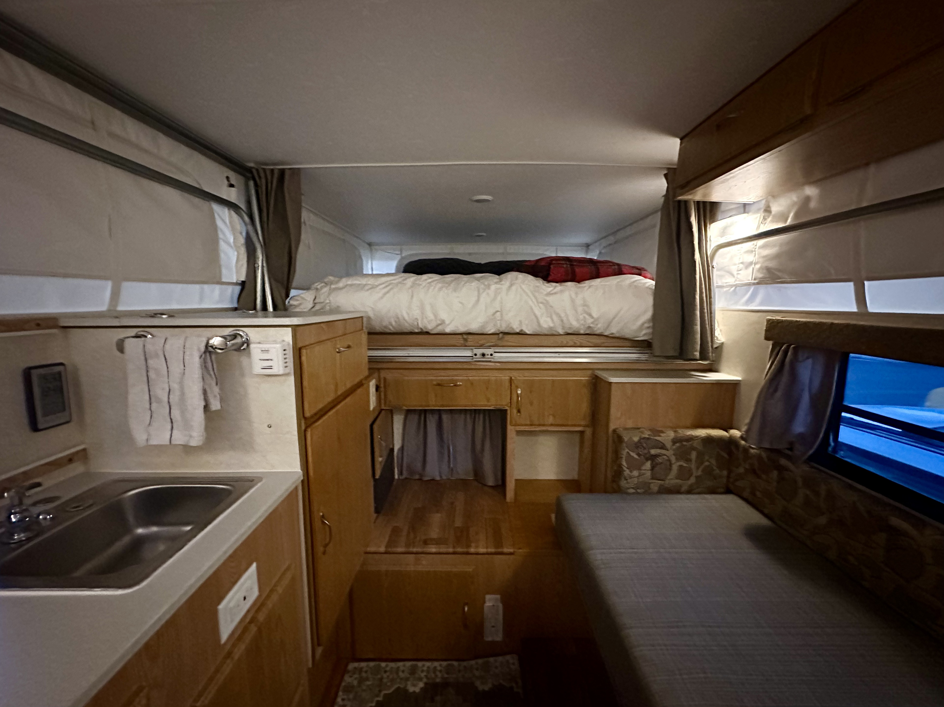 This RV rental's pop-up interior reveals an elevated bed, kitchen area with sink, and a comfortable seating lounge.. Dodge RAM 2500 2005