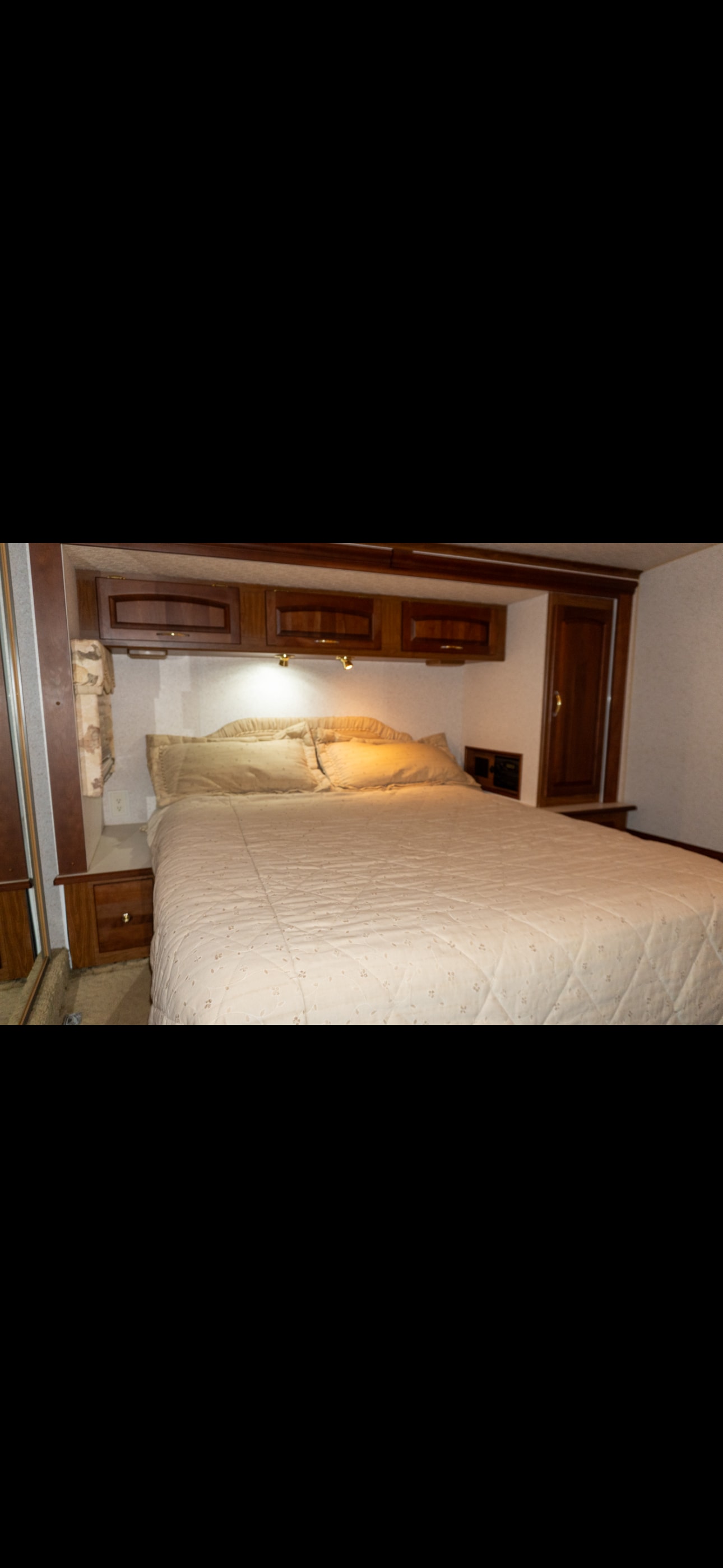 Cozy RV rental bedroom interior with a comfortable bed, overhead cabinets, and reading lights.. Itasca Horizon 2002
