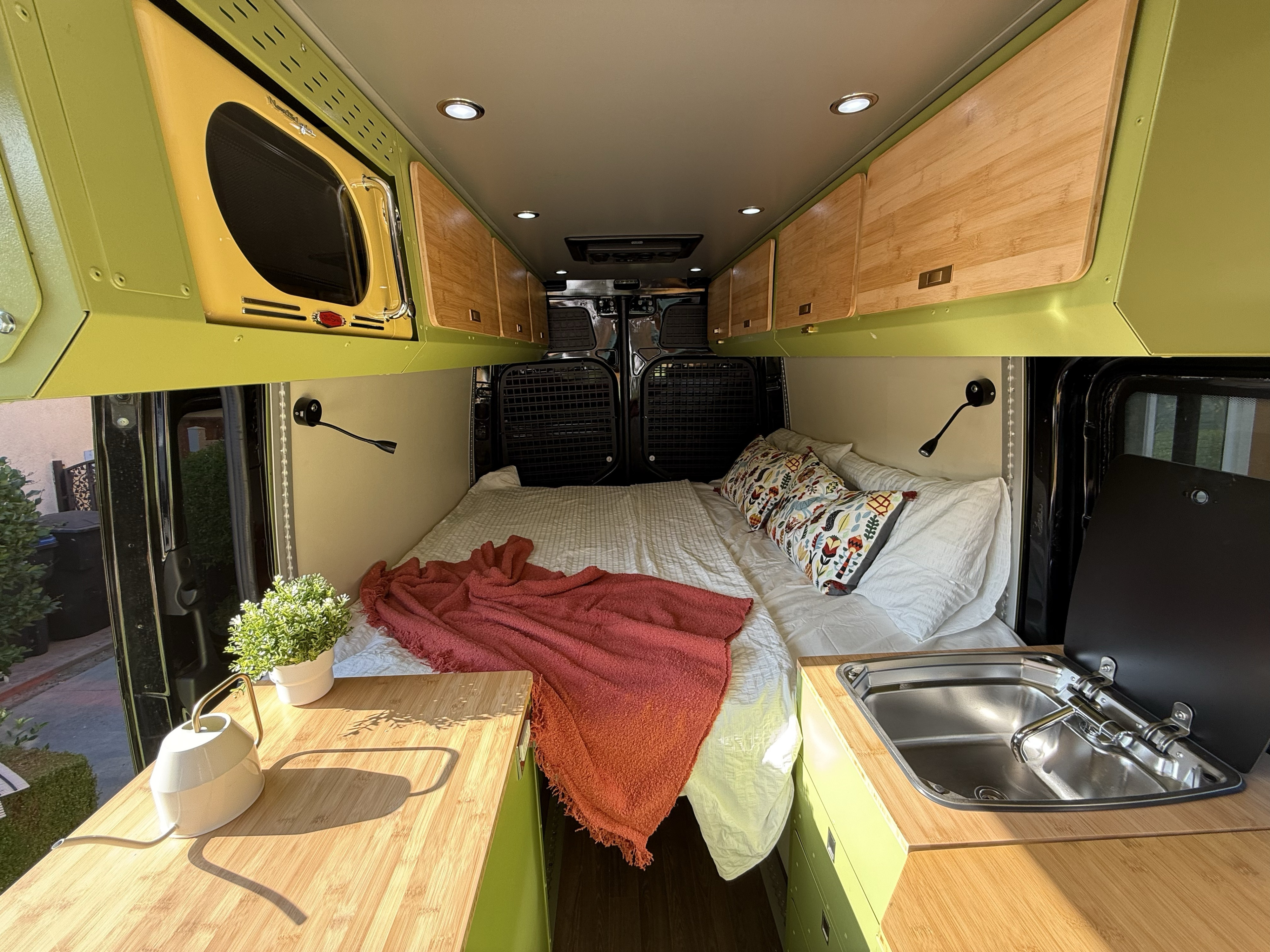 Step inside this vibrant **rv rental** camper van, featuring a comfy bed, compact kitchen with sink, and stylish olive green and bamboo storage.. MERCEDES BENZ SPRINTER 2020