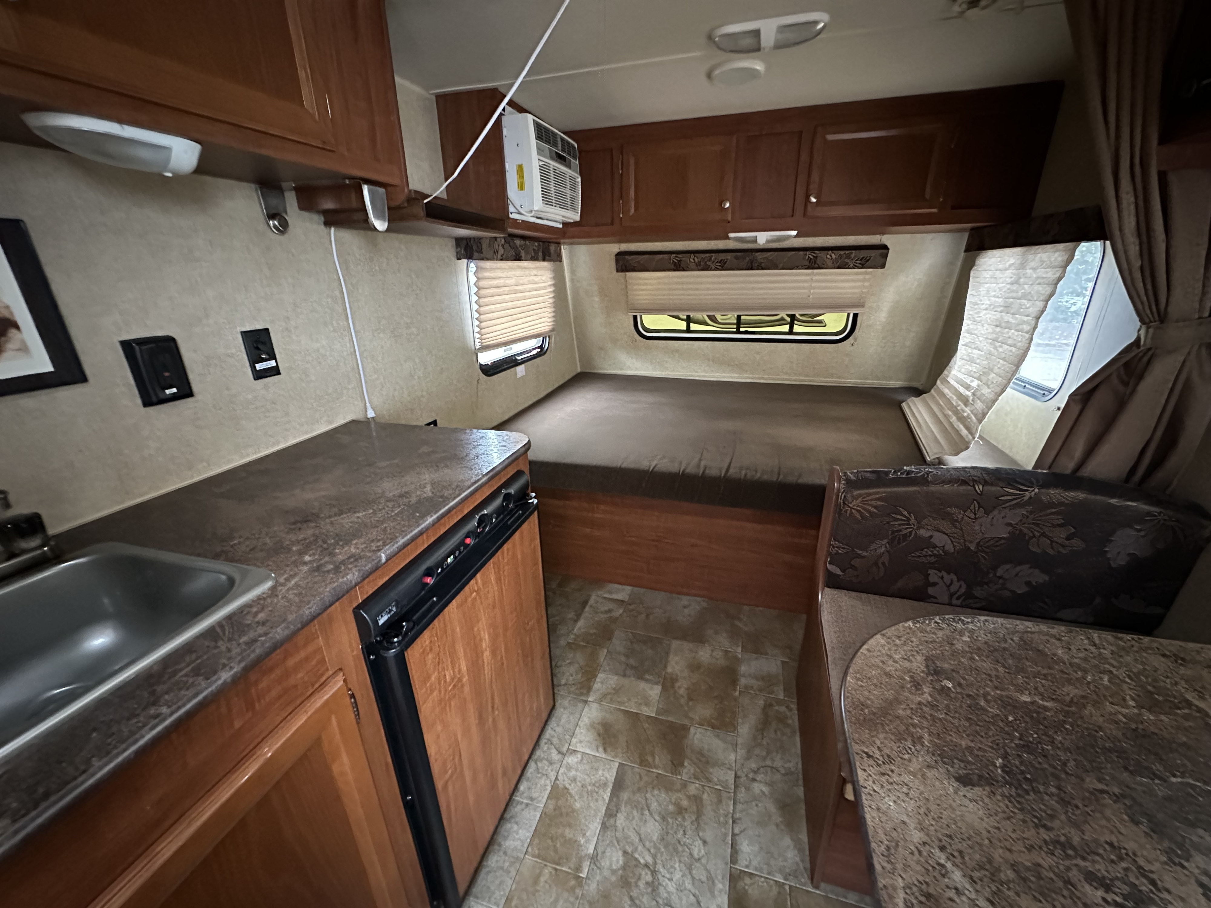 RV rental interior: kitchen with sink, compact fridge, comfortable bed, and dinette seating. Perfect for travel.. Jayco Jay Flight Swift SLX 2014