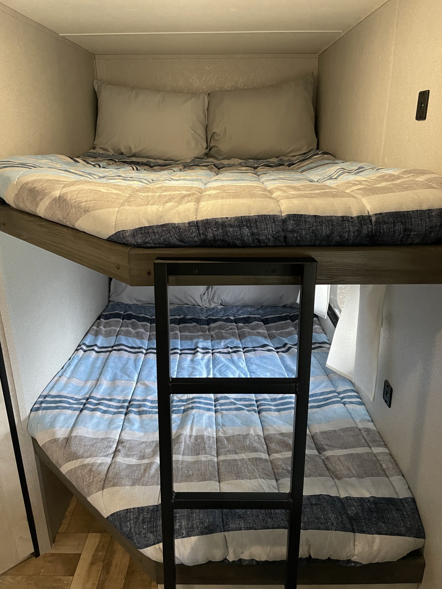 RV rental bunk beds with striped bedding and a ladder, offering cozy and compact sleeping for camping trips.. Forest River Shasta 2022
