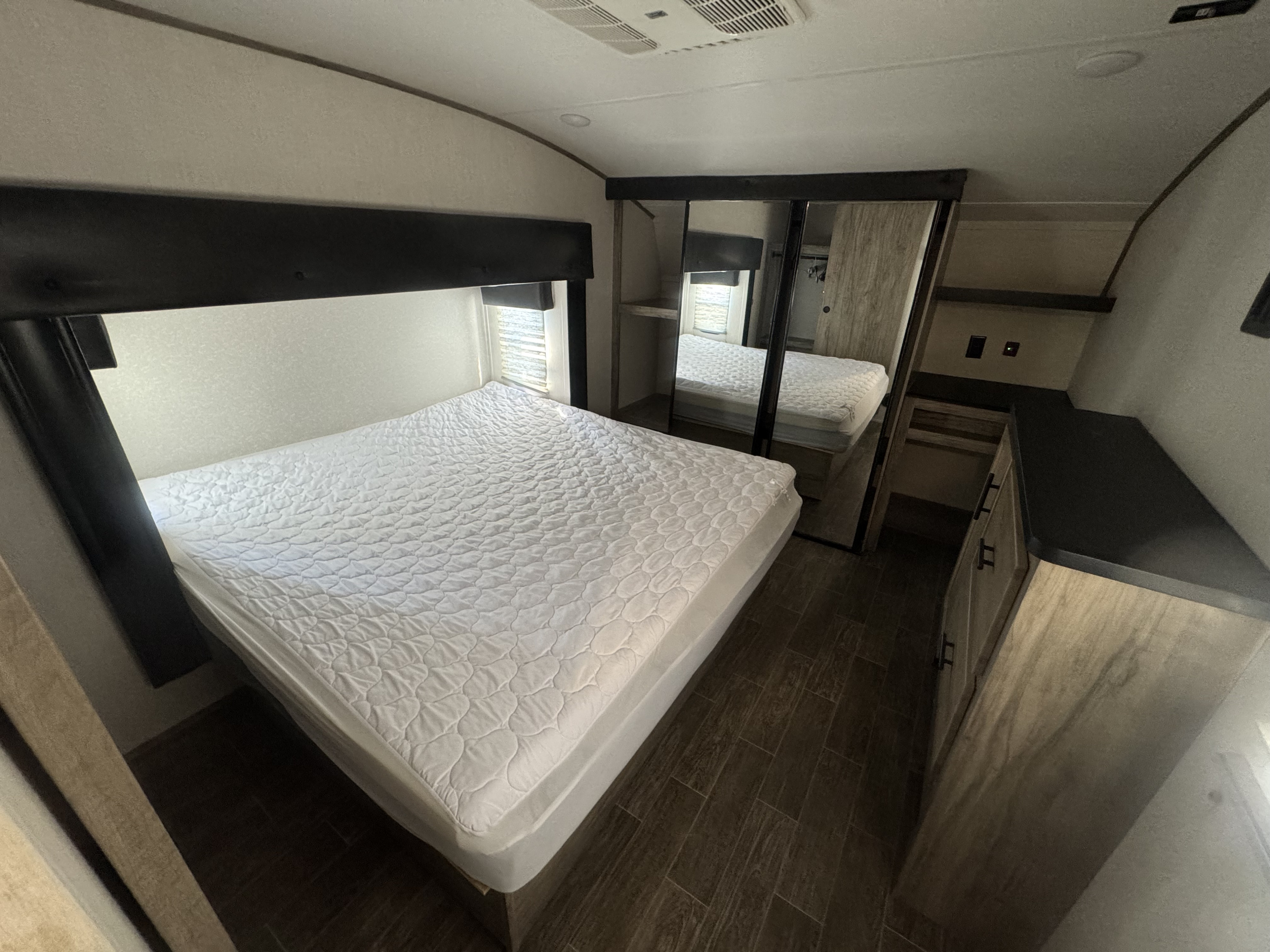 Spacious RV rental bedroom with a large bed, mirrored closet, and storage for your next adventure.. Forest River Cherokee Arctic Wolf 2022