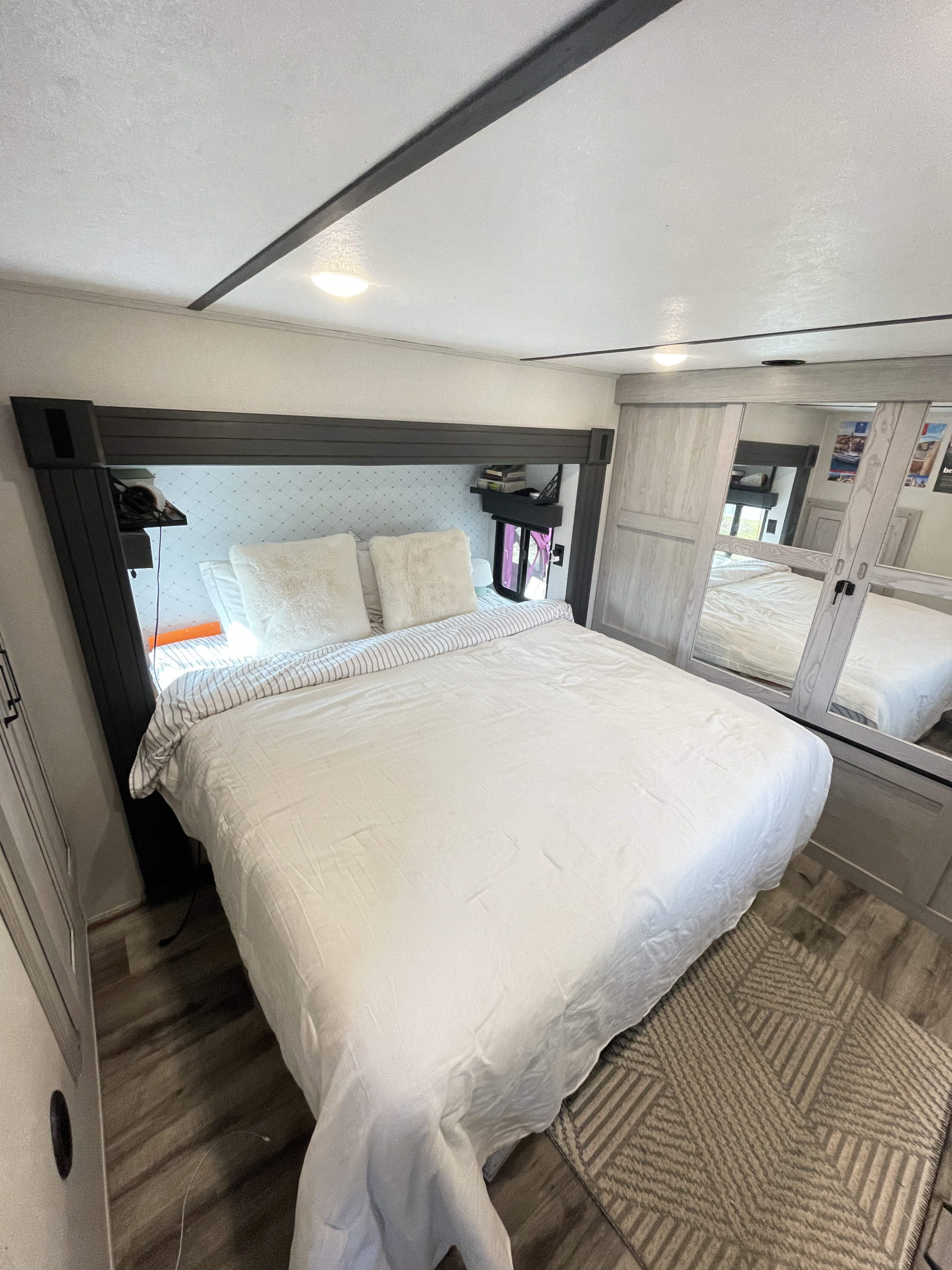 Cozy modern bedroom in an RV rental, featuring a queen bed, mirrored closet, and ample lighting for comfortable travel.. Keystone RV Montana High Country 2022