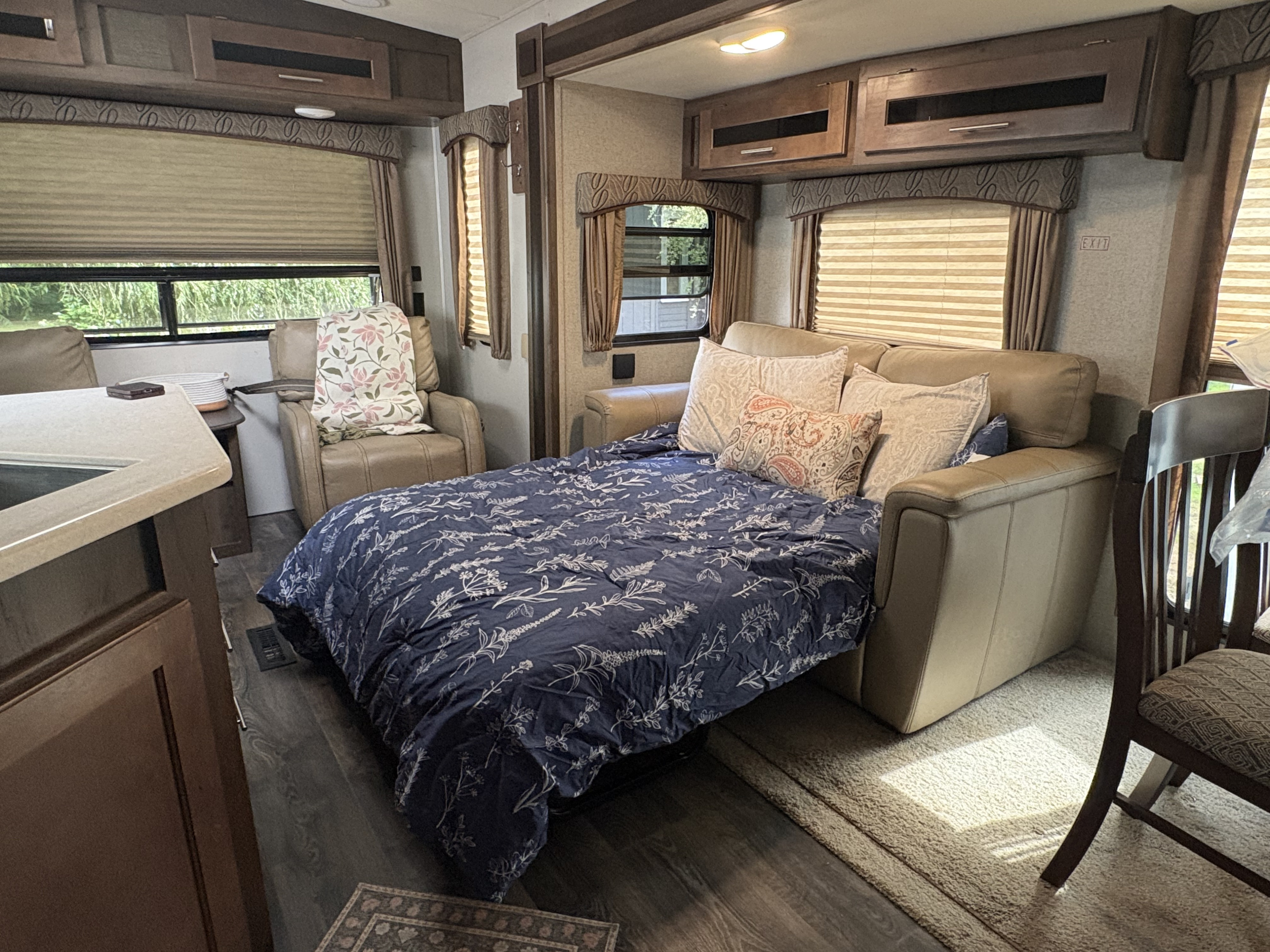 Step inside this inviting RV rental: a spacious living area with a comfy pull-out sofa, armchair, and kitchen, perfect for your journey.. Forest River Wildcat 2019