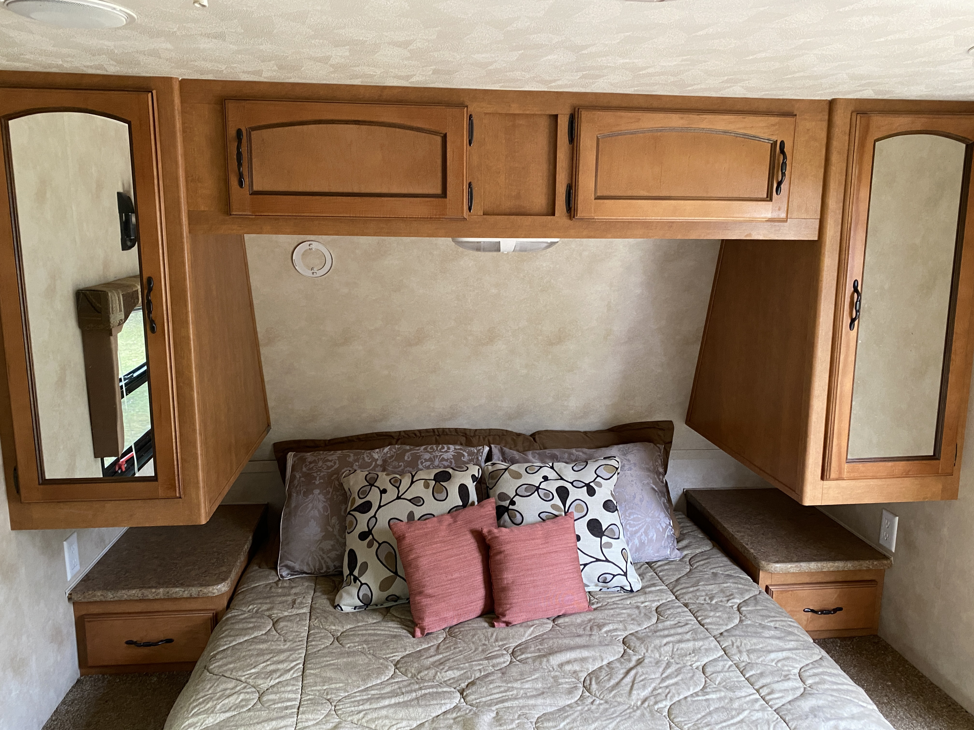 RV rental bedroom featuring a comfy bed, overhead mirrored cabinets, and convenient nightstands for your travels.. Forest River Palomino Puma 2011