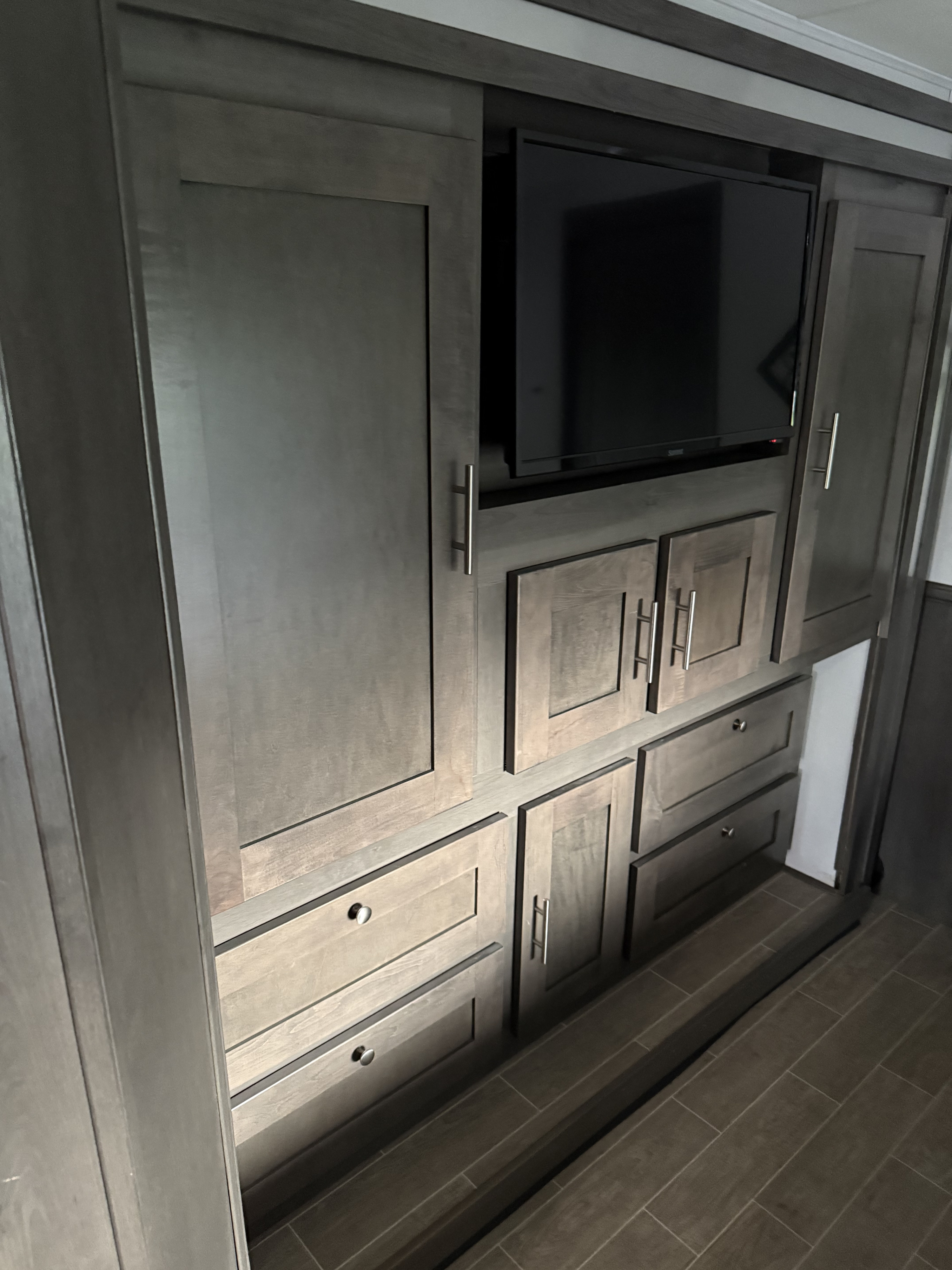 RV rental interior: dark wood entertainment center with TV, cabinets, & drawers.. Georgetown GT5 2021