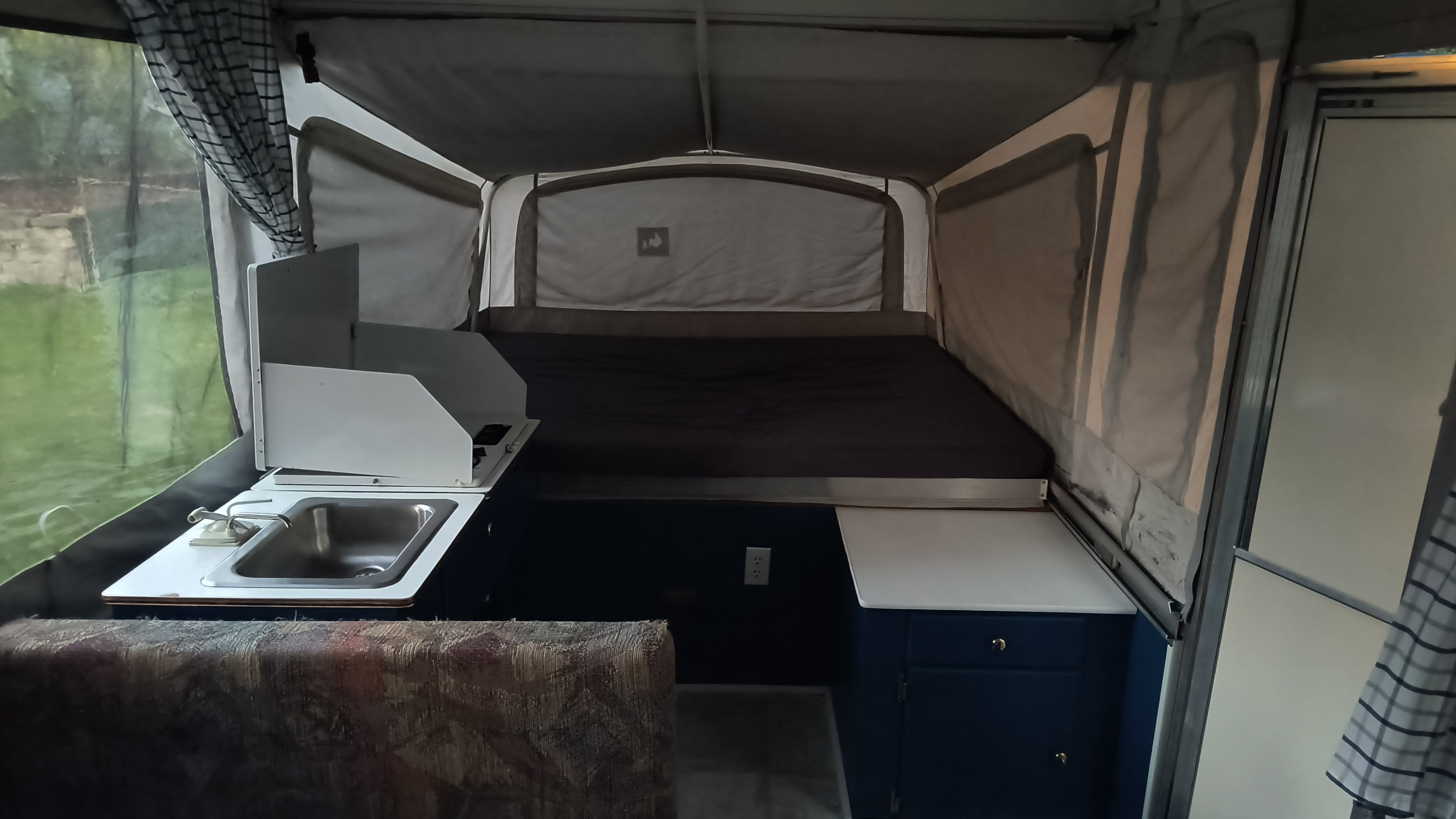 Cozy pop-up RV rental interior, with a bed, sink, and bright window for outdoor adventures.. Coleman Destiny Santa Fe 1996
