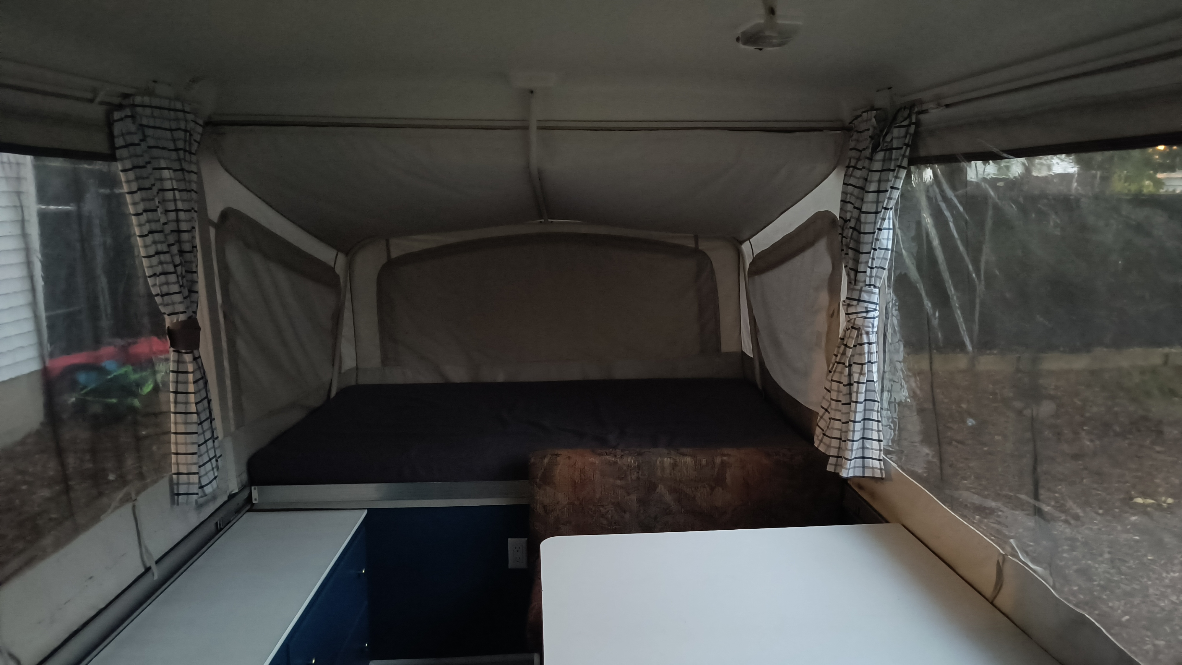 Inside an RV rental: a large bed, dining table, and plaid curtains define this pop-up camper's inviting interior.. Coleman Destiny Santa Fe 1996