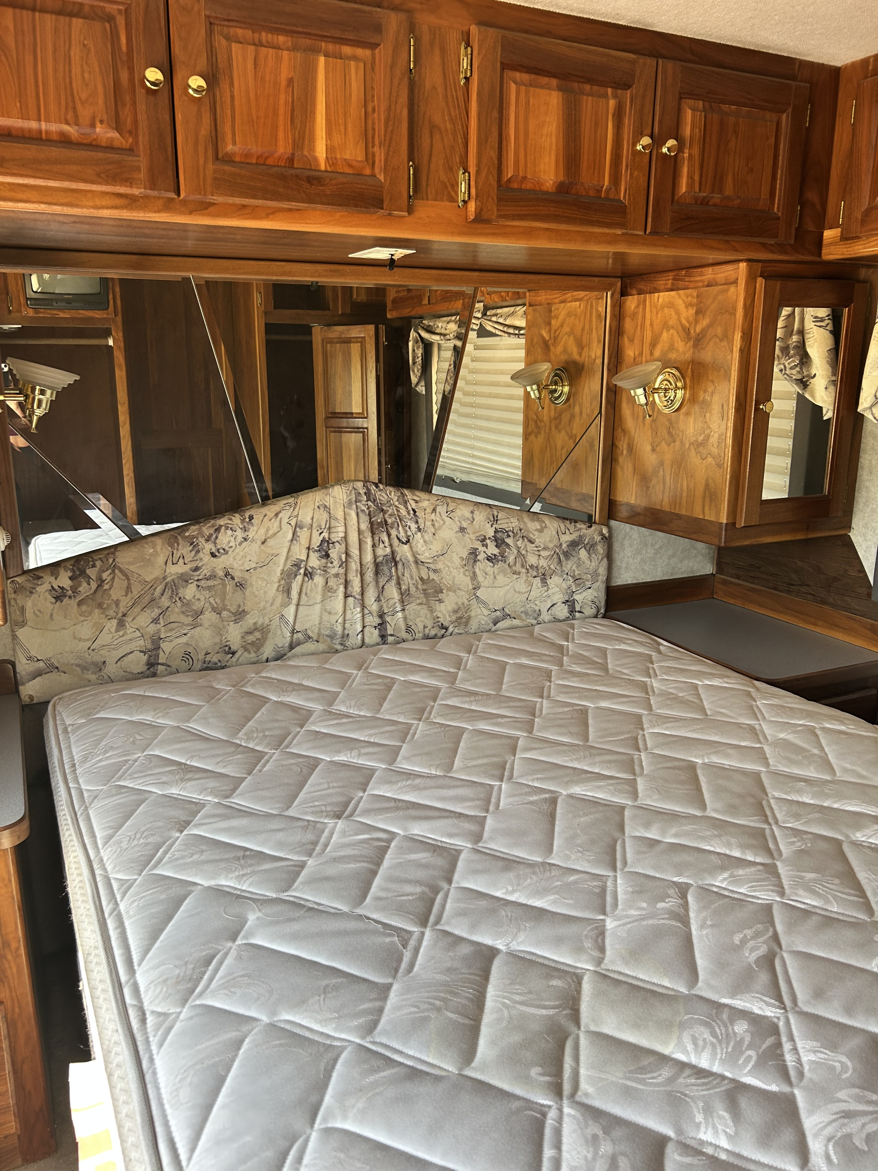 Cozy RV rental bedroom with wooden cabinets, a white quilted mattress, and integrated mirrors.. Monaco Dynasty 1997