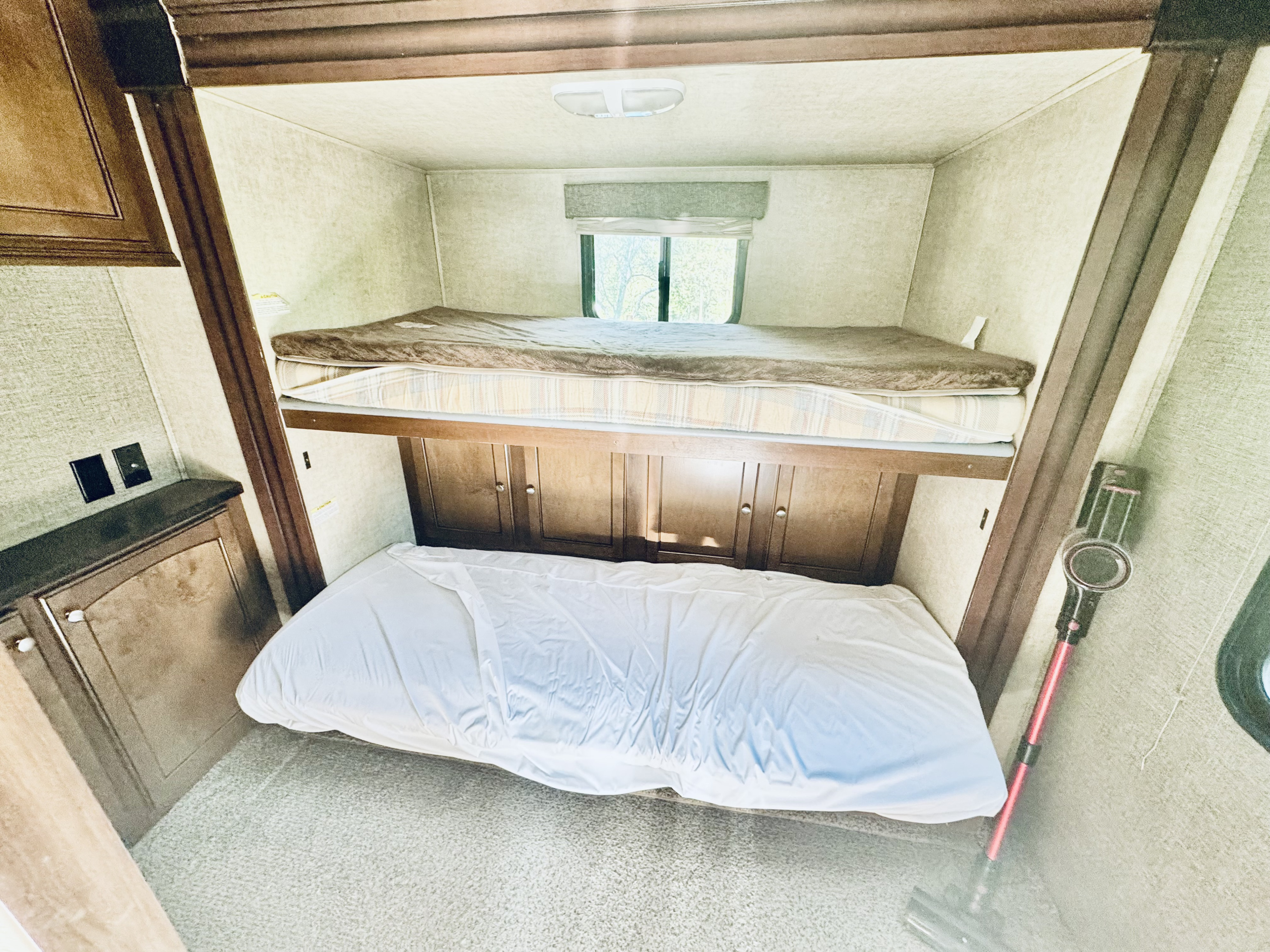 Cozy RV rental bunk beds with light-colored walls, a window, built-in storage, and a vacuum cleaner. Ideal for family.. Heartland RVs Global nomad 2020