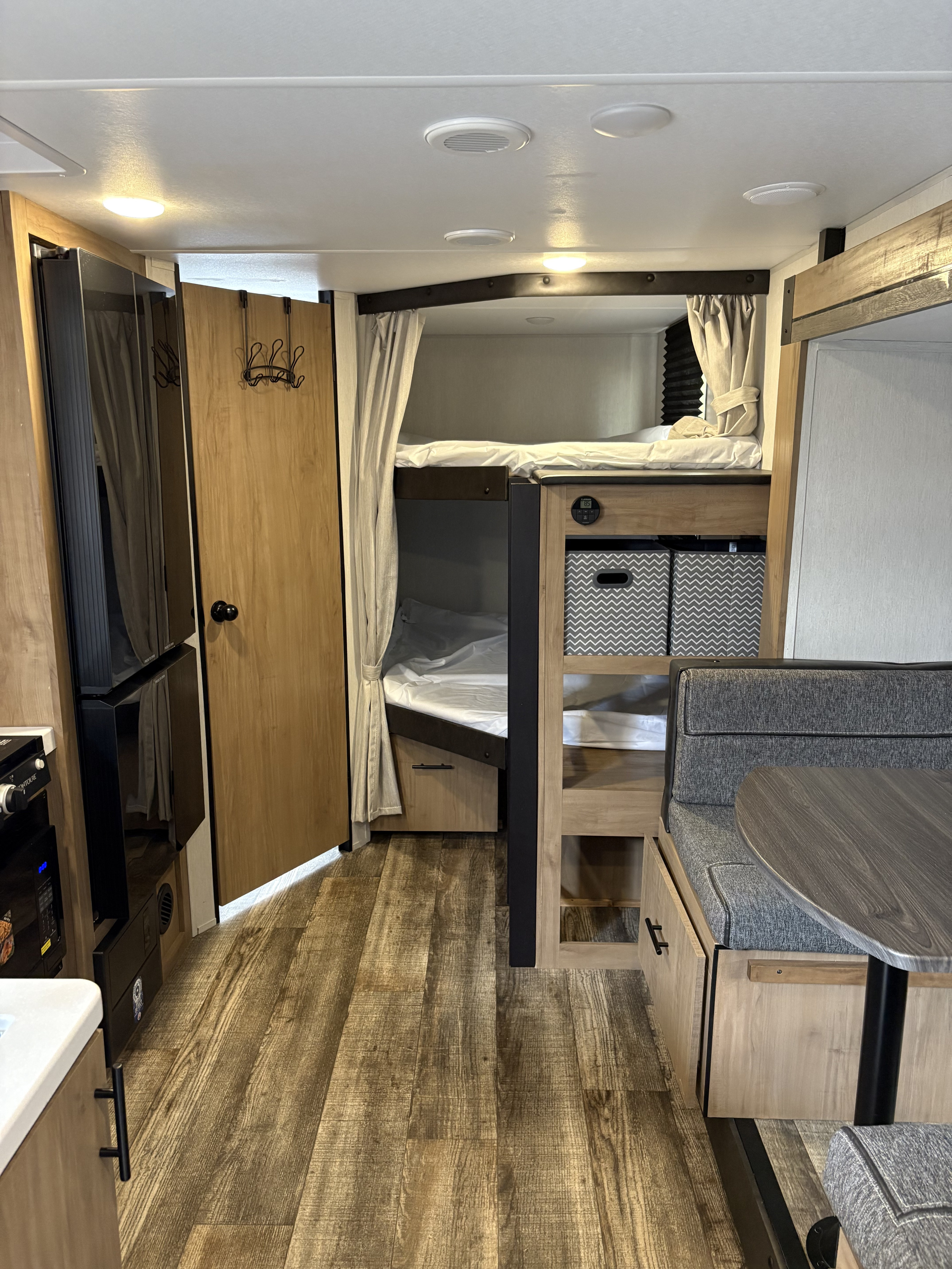 Compact RV rental interior featuring bunk beds, a dinette, and wood-look flooring, ideal for travel.. Forest River Campsite Reserve 2024