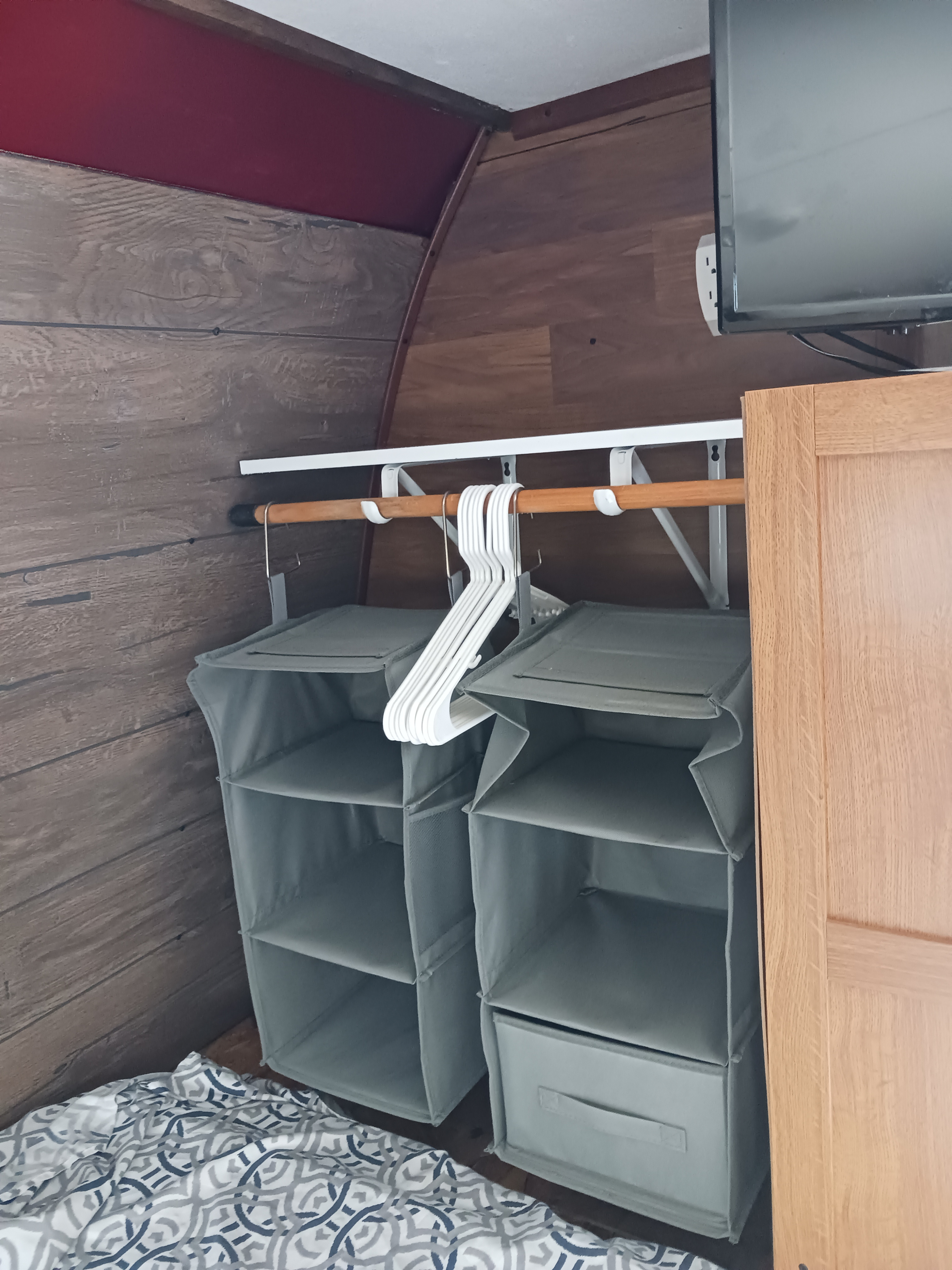 RV rental interior: efficient storage featuring hanging fabric shelves, a clothes rod, and a TV above a bed area.. Keystone RV Hideout LHS 2015