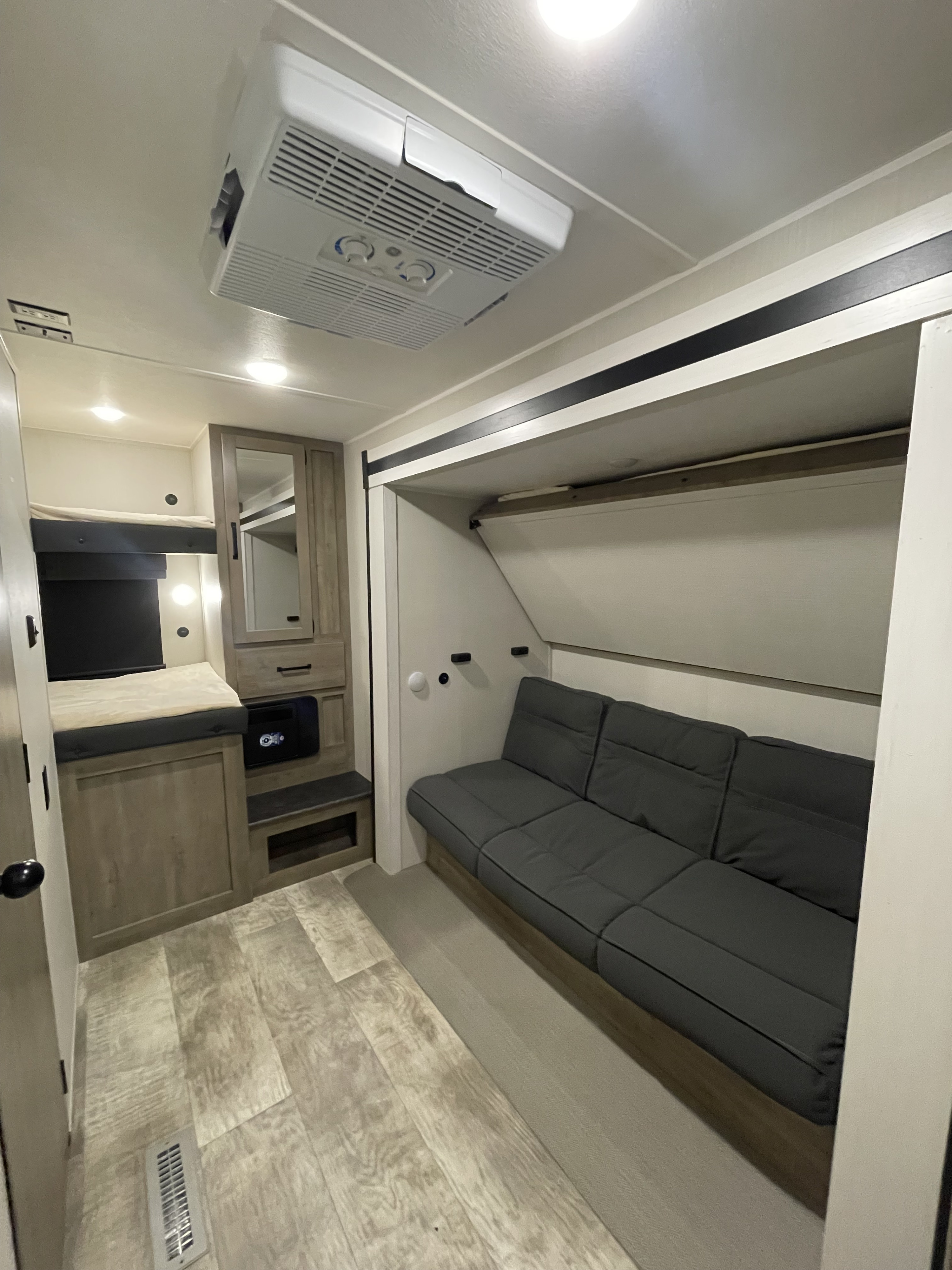 RV rental interior featuring cozy bunk beds, a convertible sofa, and an AC unit for a comfortable, compact living space.. Forest River Palomino Puma 2024