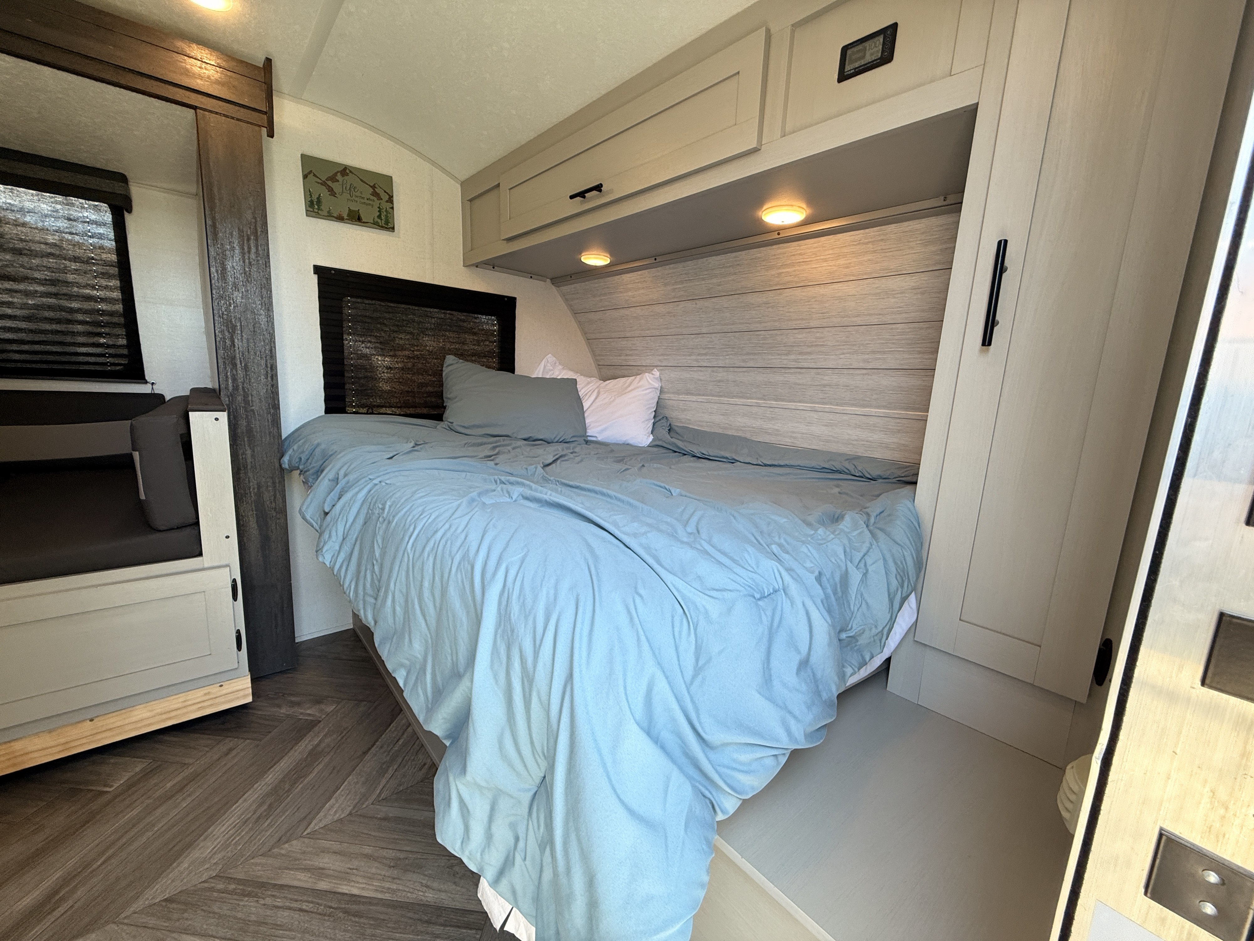 An RV rental bedroom with a cozy bed, bunk beds, light wood cabinets, and dark wood herringbone floors.. Forest River Salem FSX 2021