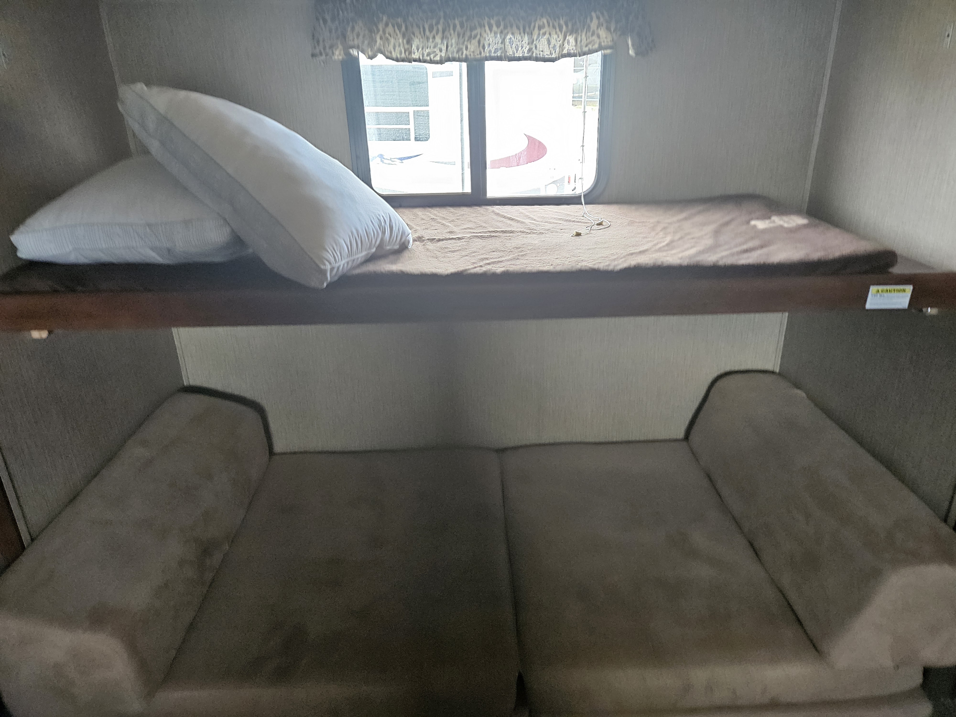 Inside an RV rental: a cozy bunk bed with pillows and a sofa below, great for travel and comfort.. Keystone RV Passport Grand Touring 2016