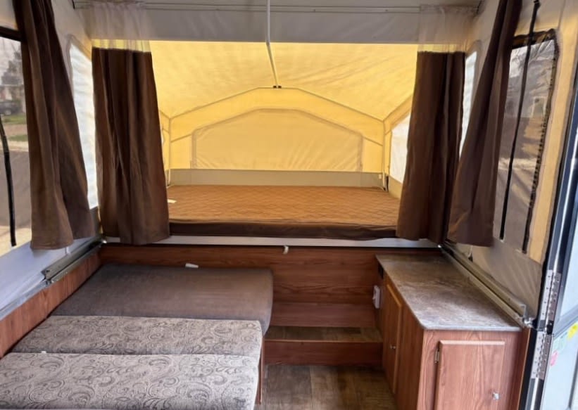 Interior of an RV rental: cozy pop-up camper with a bed, seating, and counter space. Perfect for travel.. Rock wood 1940 LTD 2016