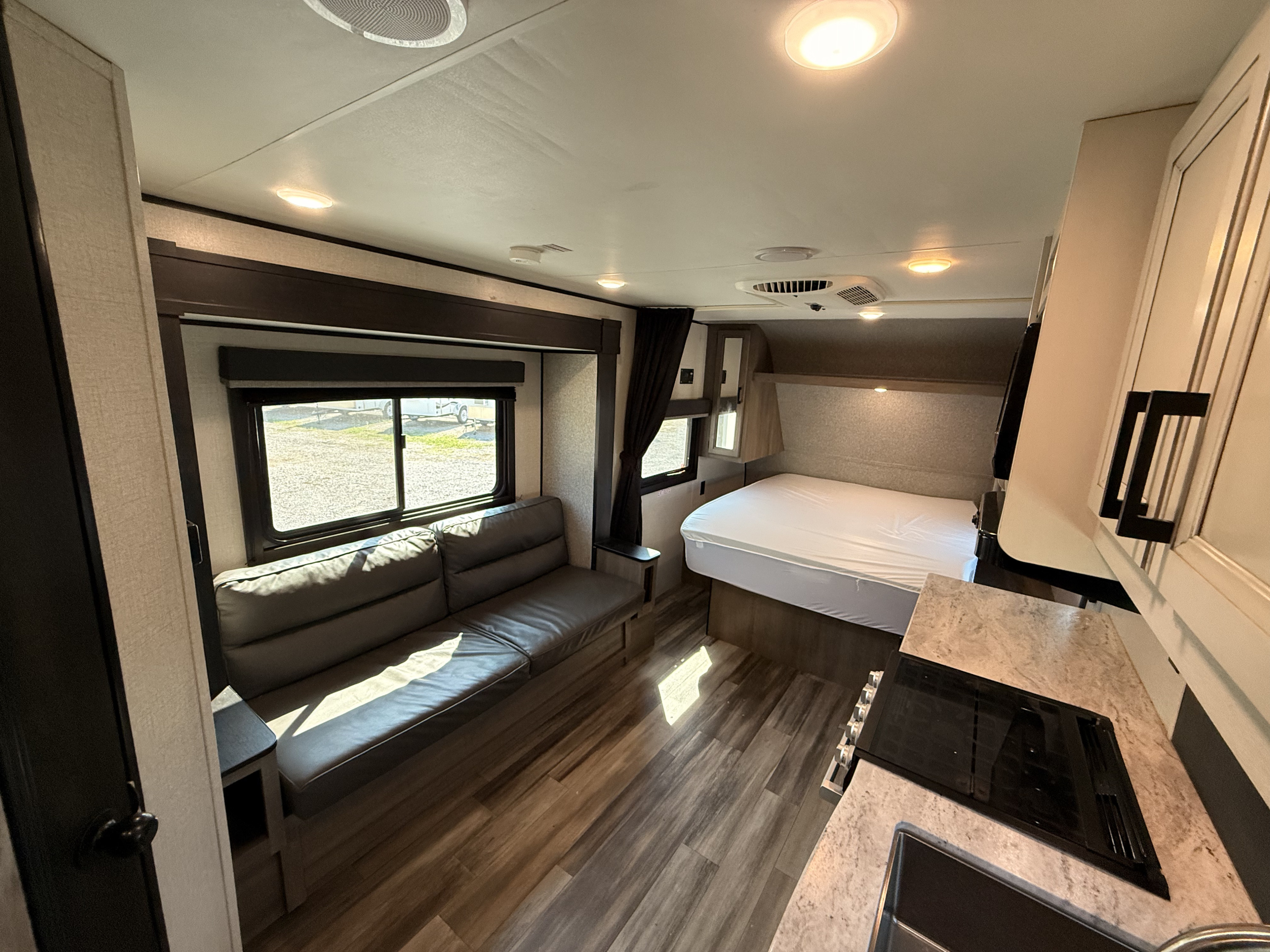 RV rental interior featuring a spacious sofa, inviting bed, and compact kitchen area. Bright and functional layout.. Highland Ridge RV Open Range 2022