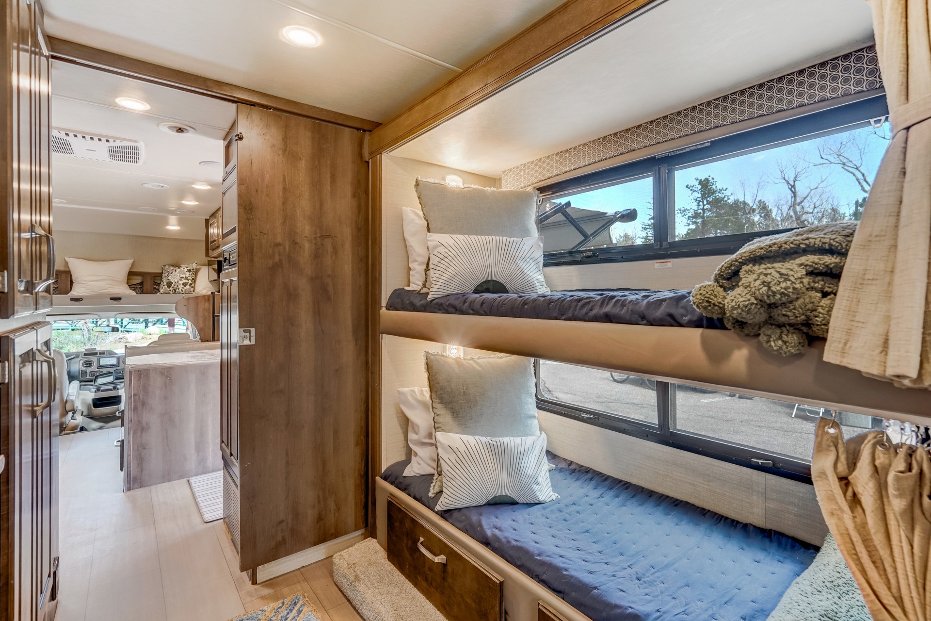 Spacious RV rental interior featuring cozy bunk beds, a forward living area, and natural light, perfect for family adventures.. Jayco Greyhawk 2018