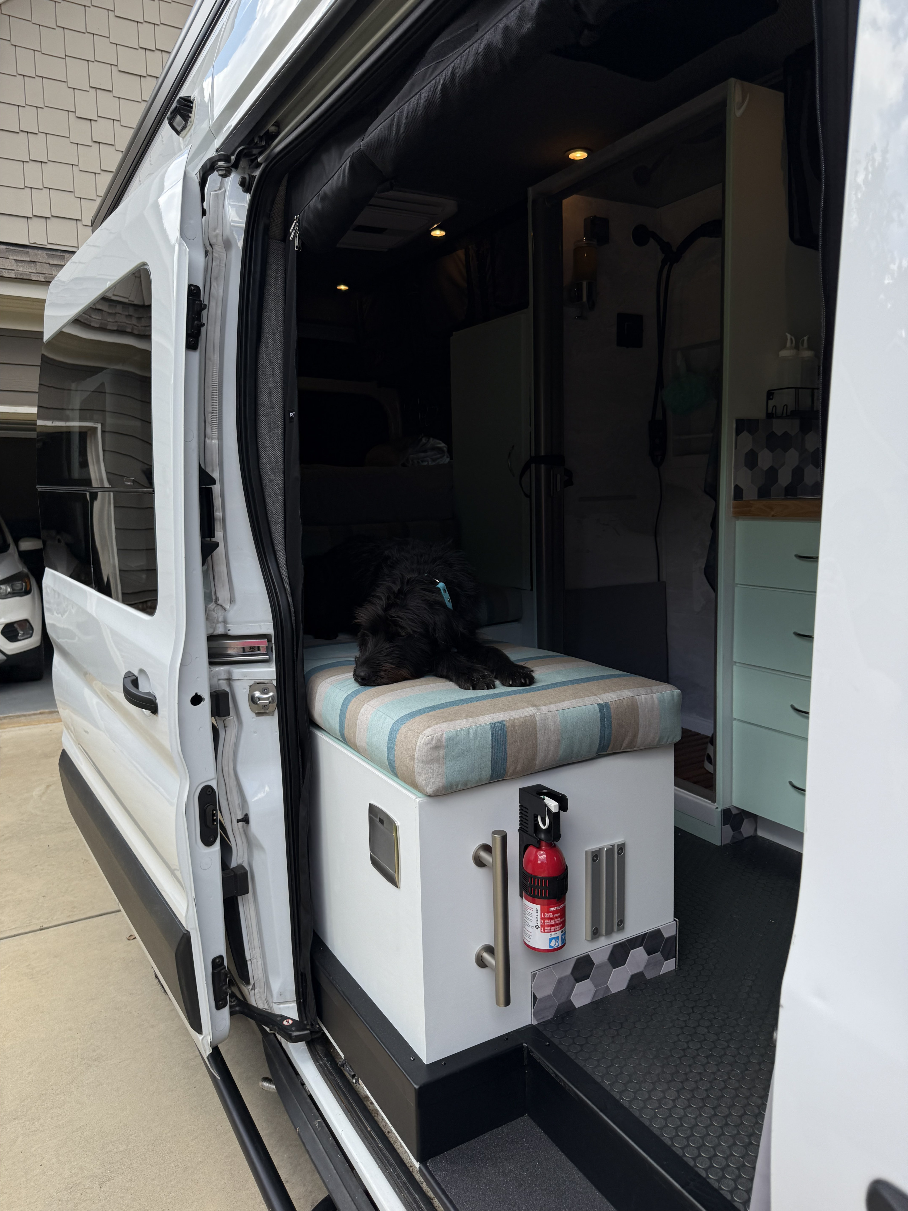 An RV rental's inviting interior features a black dog on a striped bench, custom built-ins, and a fire extinguisher.. Ford Ford F150 2023