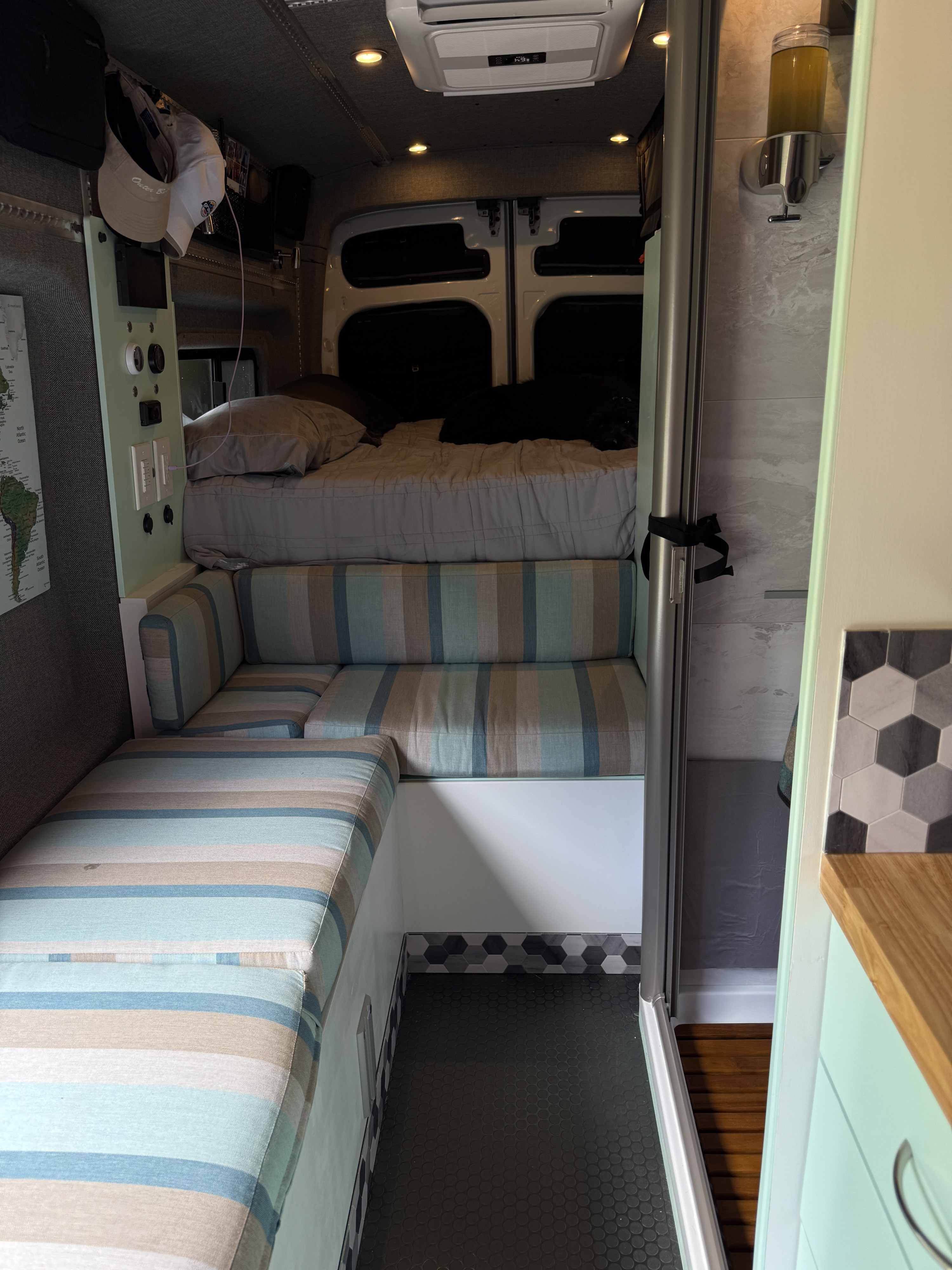 This RV rental features a comfortable bed, striped lounge, control panel, and a built-in shower, optimizing compact living.. Ford Ford F150 2023