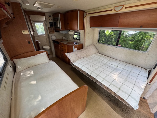 Inside an RV rental: cozy twin beds, compact kitchen, and bath. Explore comfort on the road.. Itasca Navion 2006