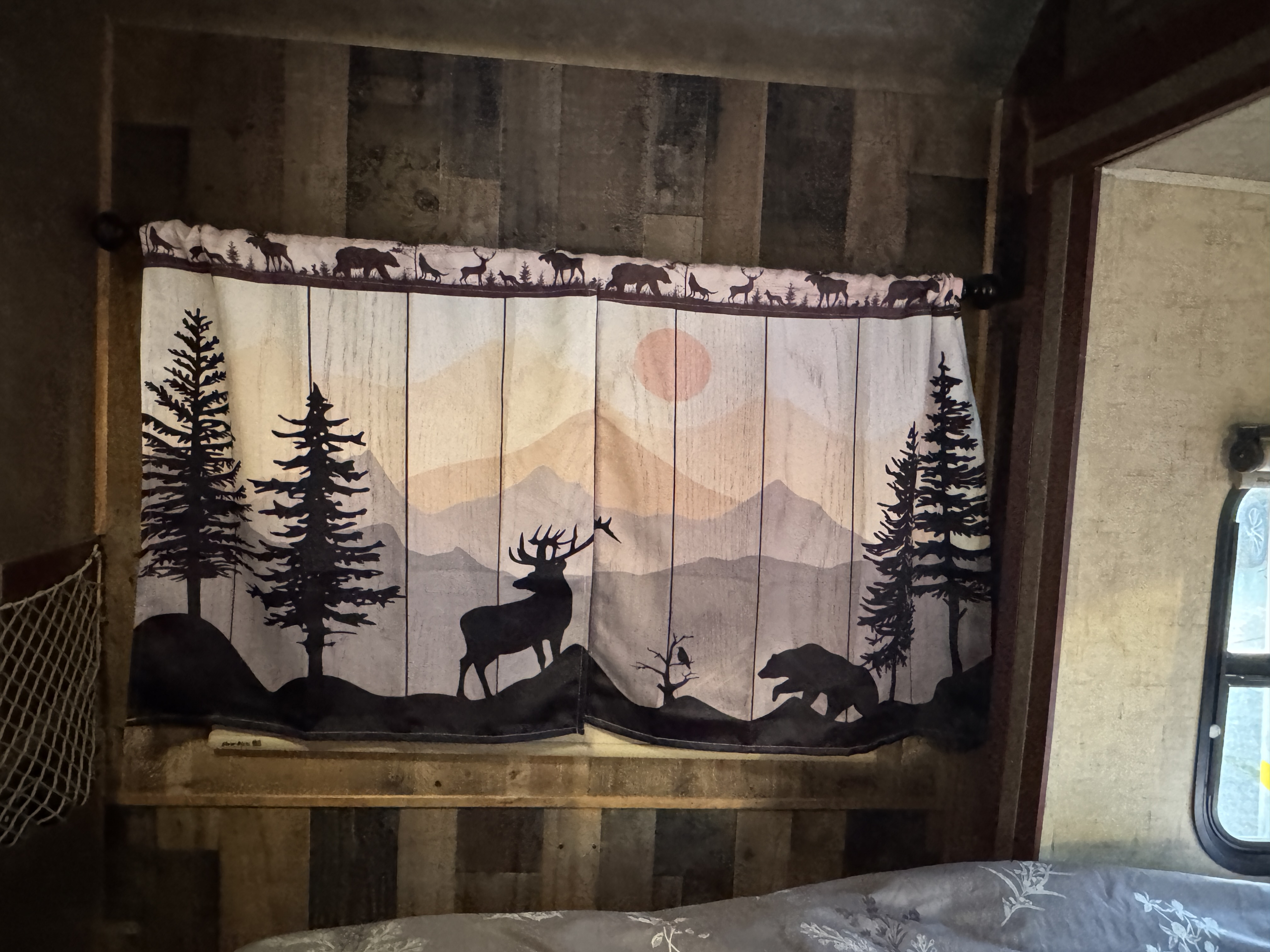 RV rental bedroom with a forest-themed curtain showing deer, bears, moose, and pine trees; rustic wood walls.. Forest River Sunseeker MBS 2016
