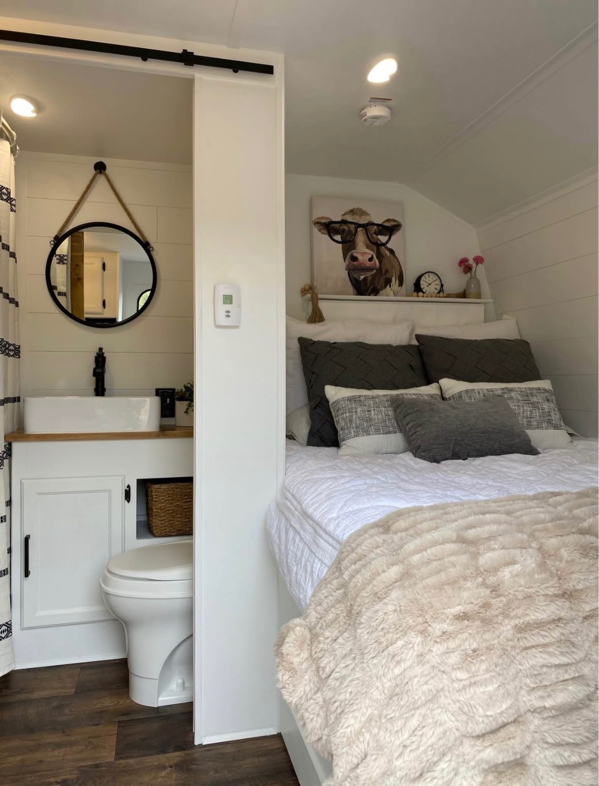 This RV rental showcases smart design: a cozy bedroom with a cow art print, separated from a compact bathroom by a barn door.. Keystone RV Springdale 2017