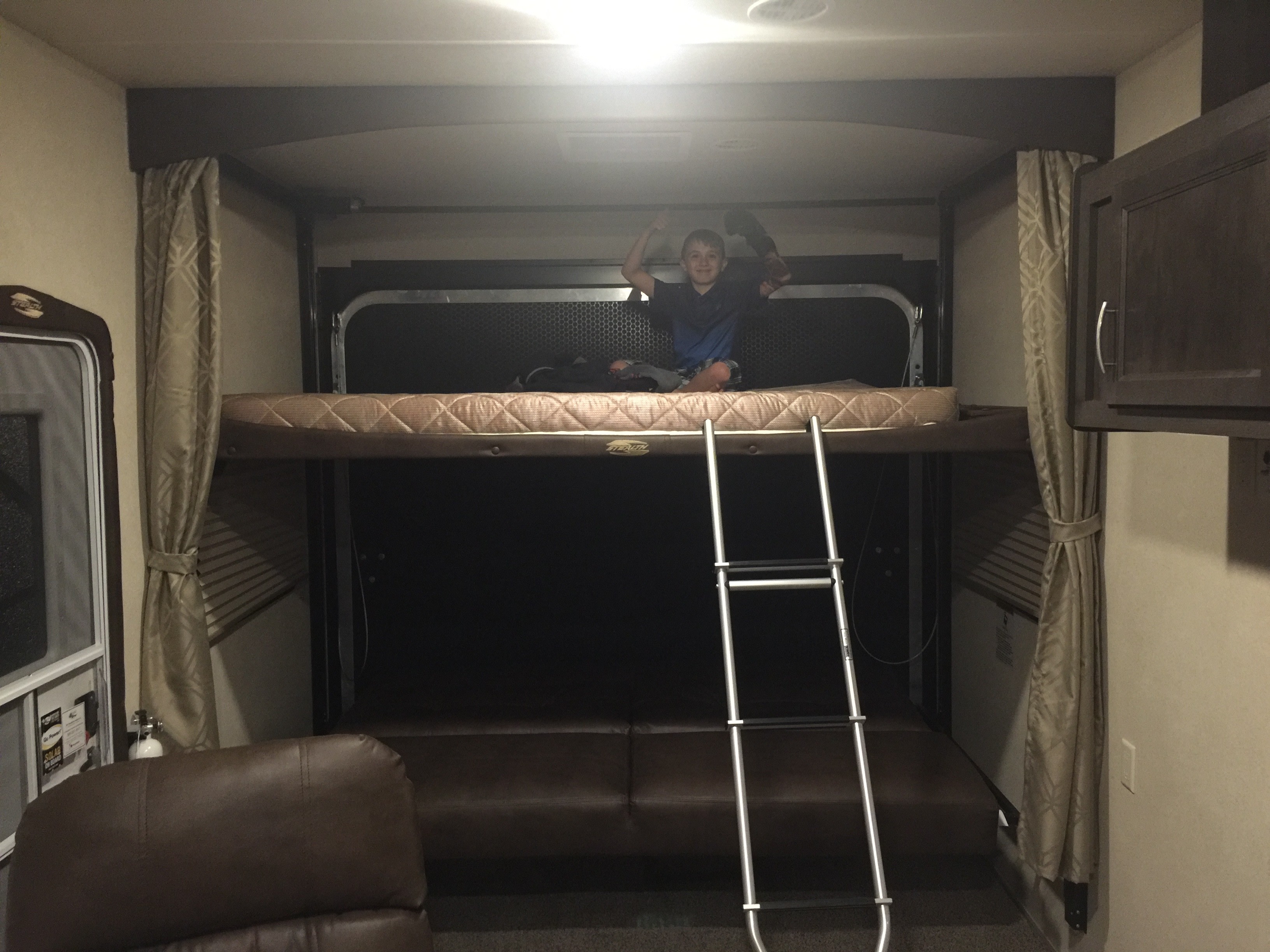 An RV rental with a happy boy on bunk beds, showing the comfy interior perfect for family travel.. Forest River FQ2916 Toy Hauler 2017