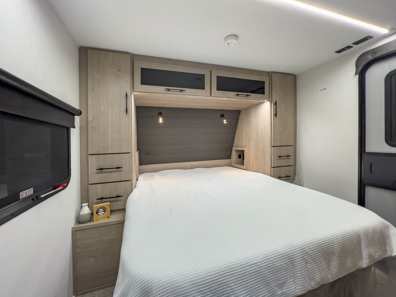 Cozy RV rental bedroom with a comfortable bed, integrated storage, and TV, ideal for road trips and travel.. Grand Design Imagine XLS 2025