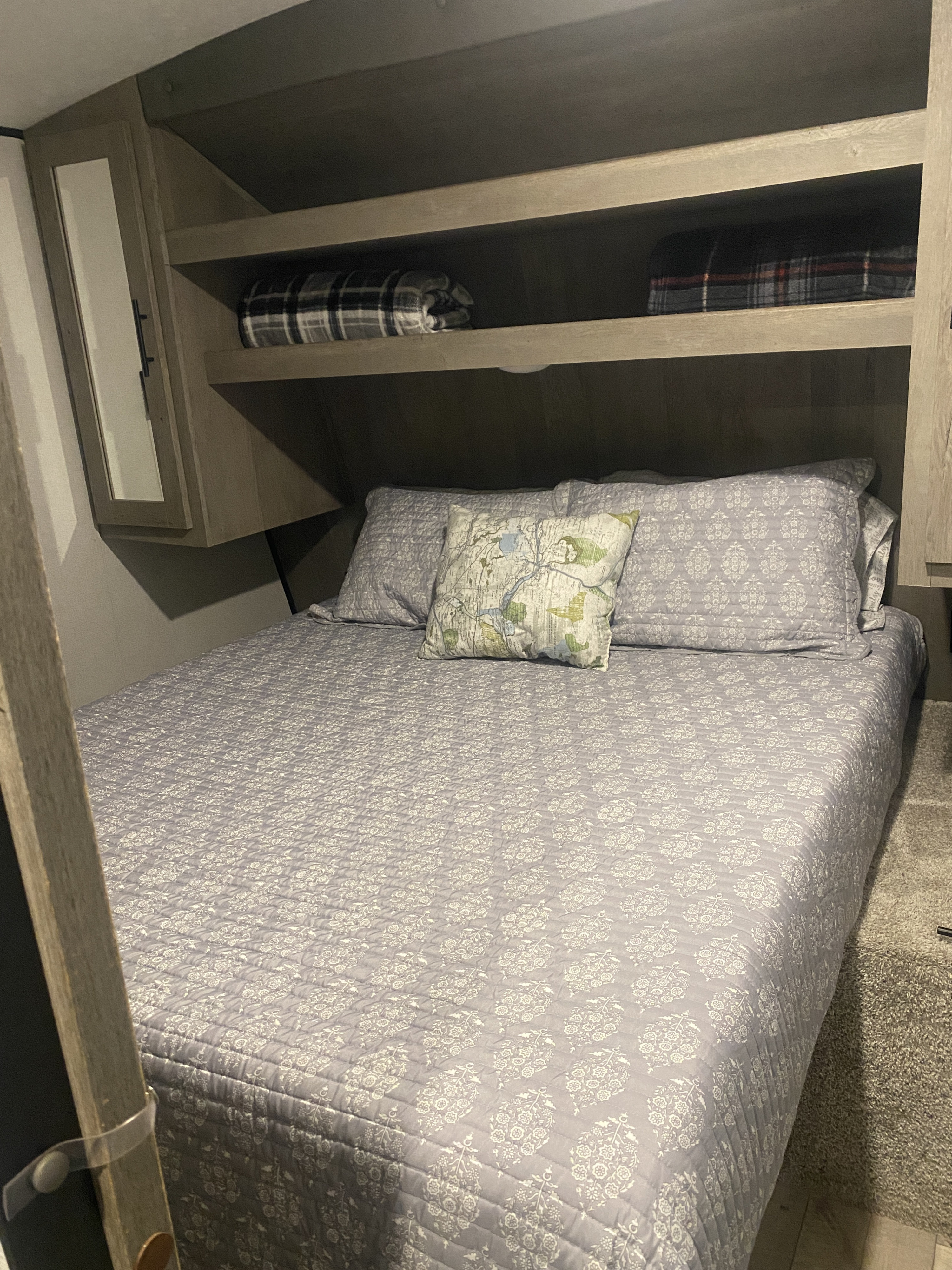 Enjoy a comfortable night's sleep in this cozy RV rental bedroom. Features include a patterned bed & overhead storage.. Keystone RV Springdale 2021