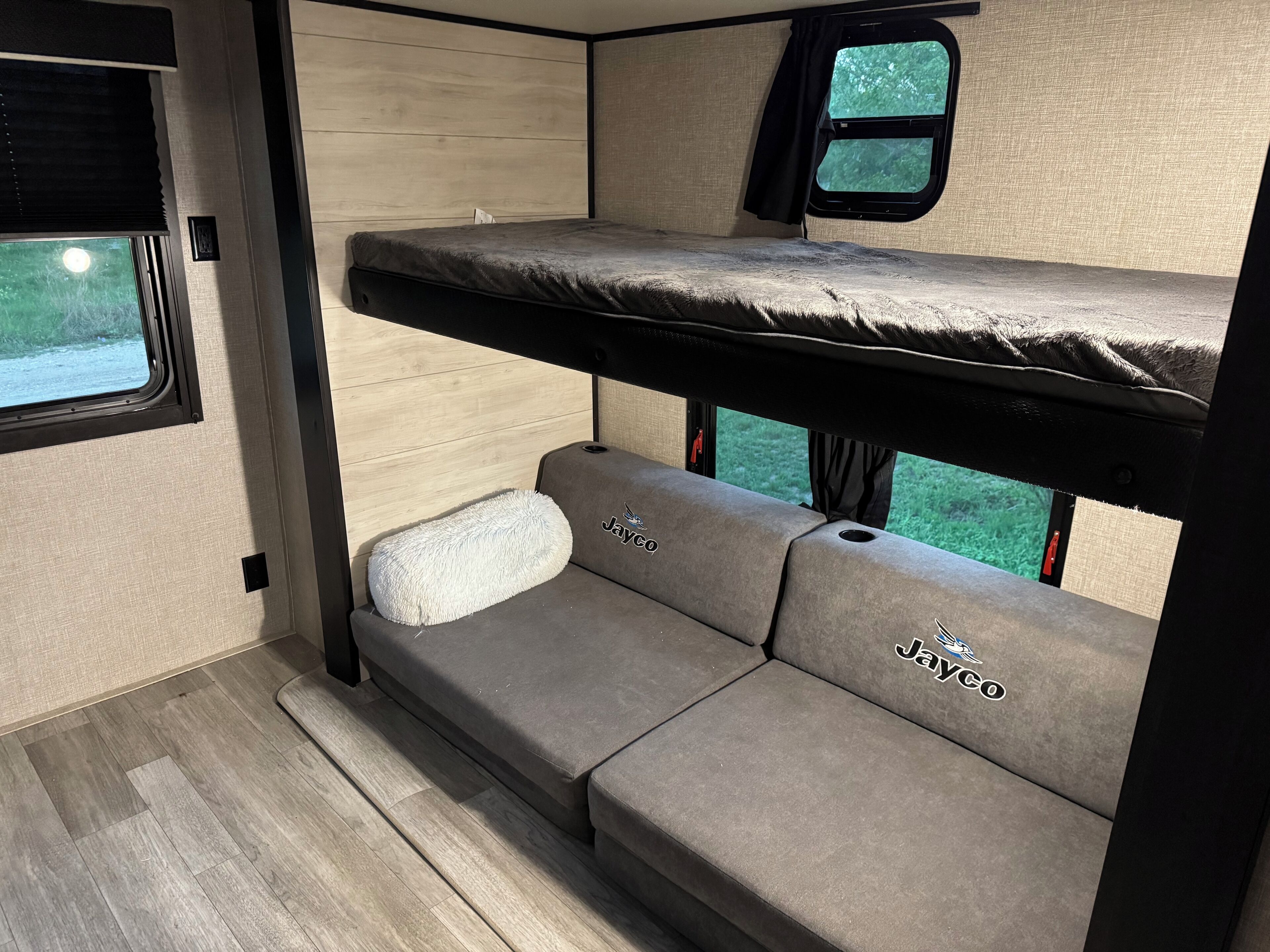 This RV rental features a comfortable bunk bed above a versatile sofa with cup holders, alongside large windows for scenic views.. Jayco Jay Flight 2022