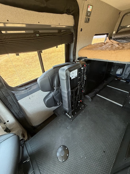 Inside an rv rental van conversion: flexible seating, cozy elevated bed, and large windows with outdoor views. Ready for adventure!. Mercedes-Benz Sprinter 2022