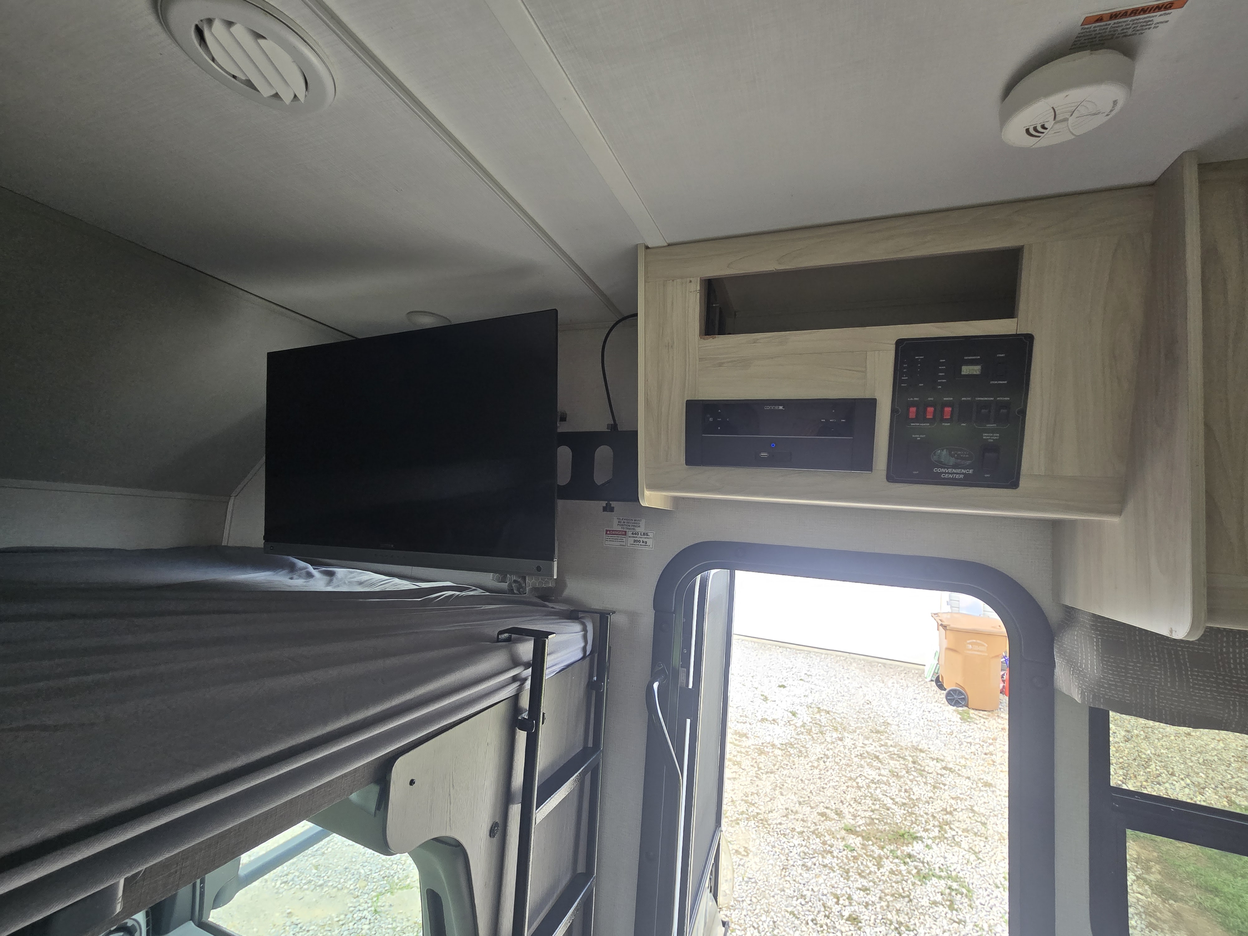 RV rental's interior featuring a bunk bed, wall-mounted TV, convenience center, and outside view.. Forest River Sunseeker LE 2022