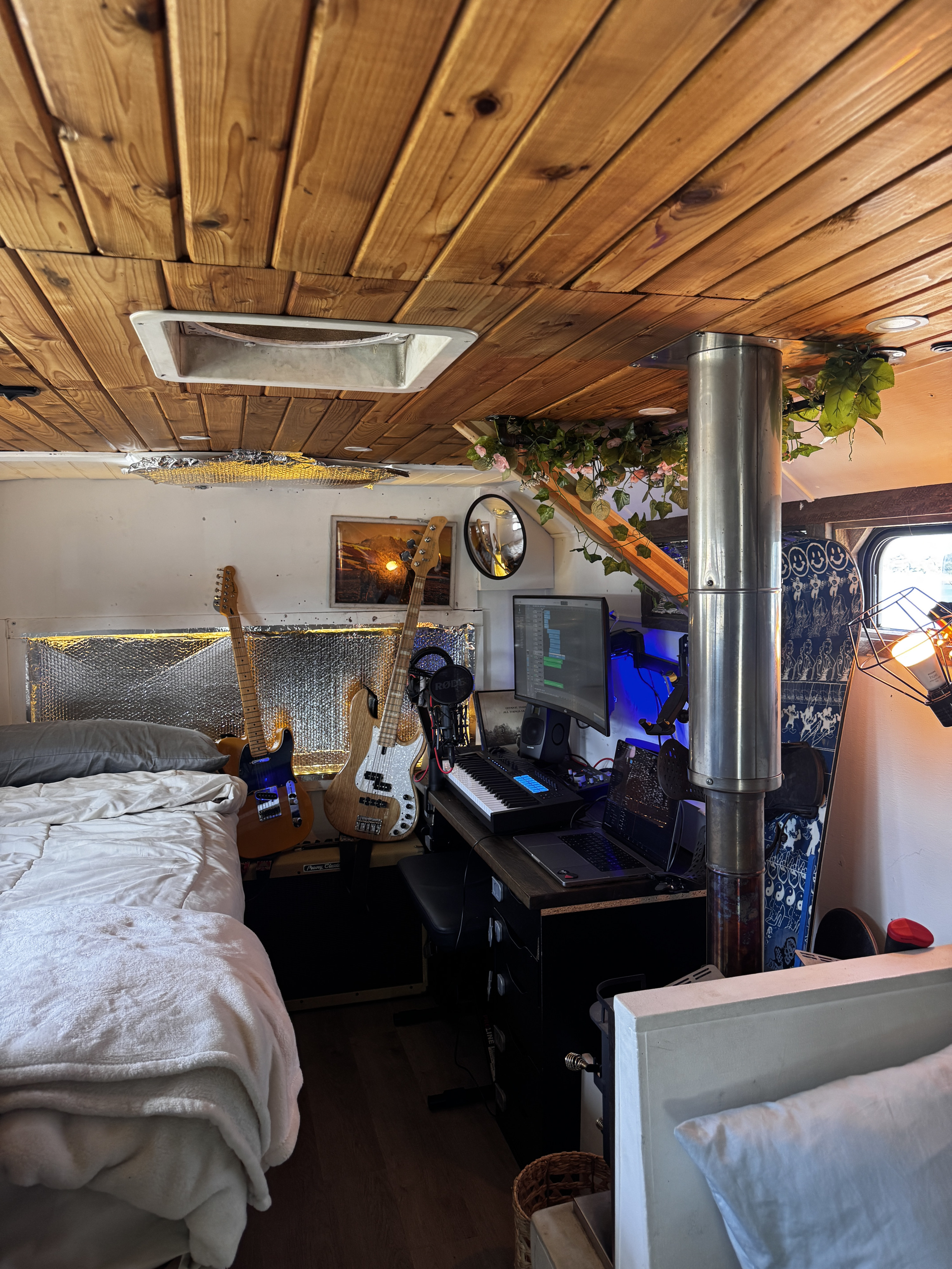 Unique RV rental interior: a cozy bed, rustic wood ceiling, and a compact music studio with guitars, ideal for mobile creativity.. Ford E450 2005