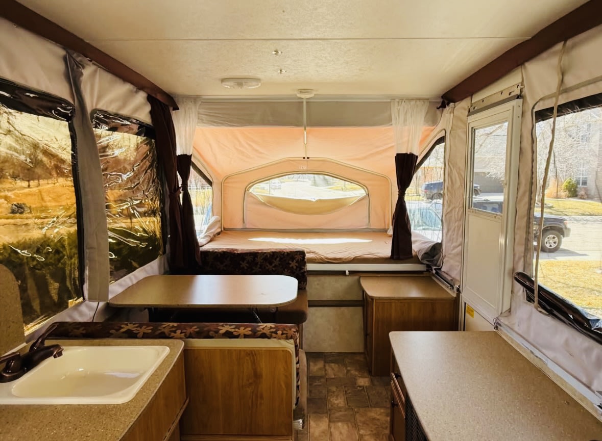 Spacious pop-up camper interior, perfect for your next rv rental, featuring beds, dining area, and a kitchen sink.. Forest River Palomino 2011