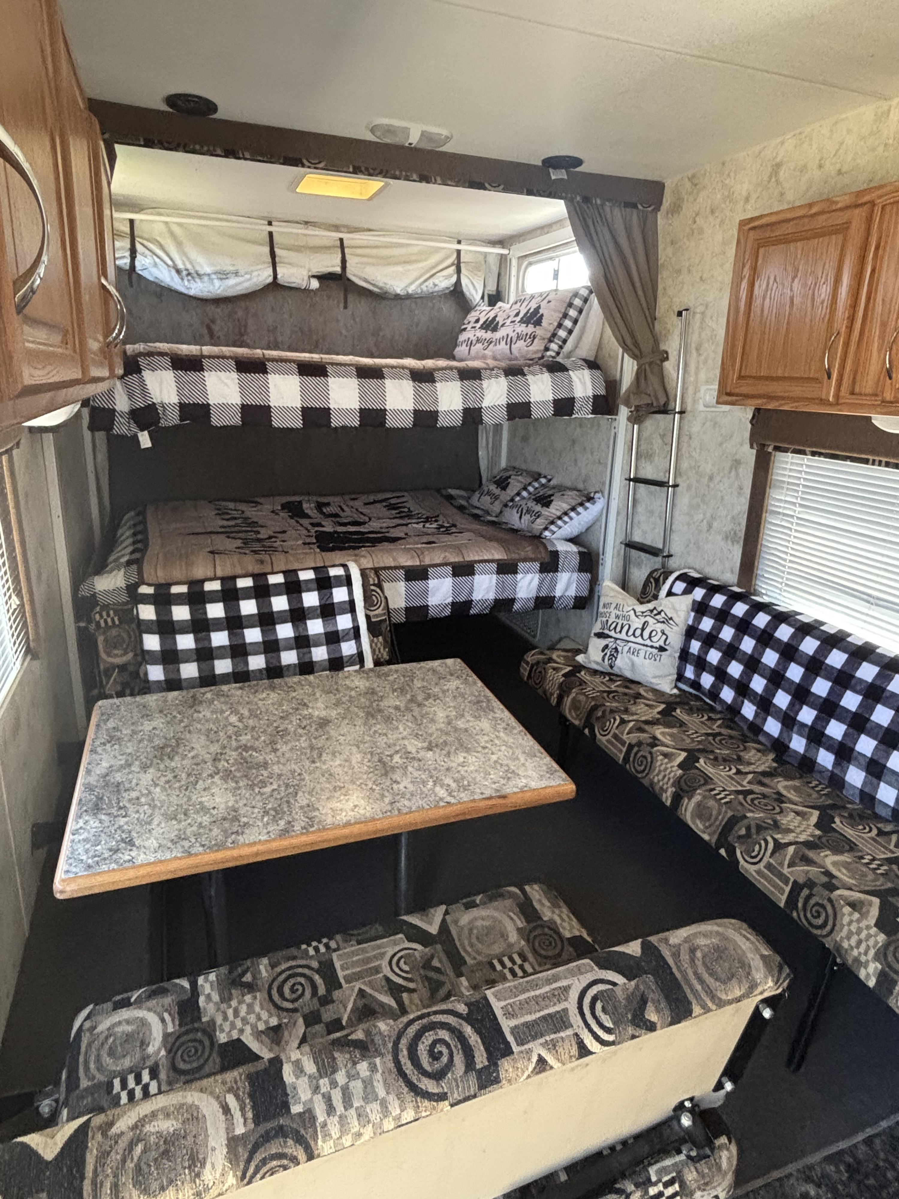RV rental interior features bunk beds with black and white buffalo check bedding, a dining table, and patterned benches.. Eclipse Recreational Vehicles Attitude 2006