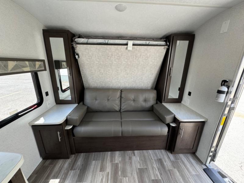 Compact RV rental interior features a versatile sofa, folds-down bed, and storage cabinets for efficient living.. Forest River Wildwood X-Lite 2019