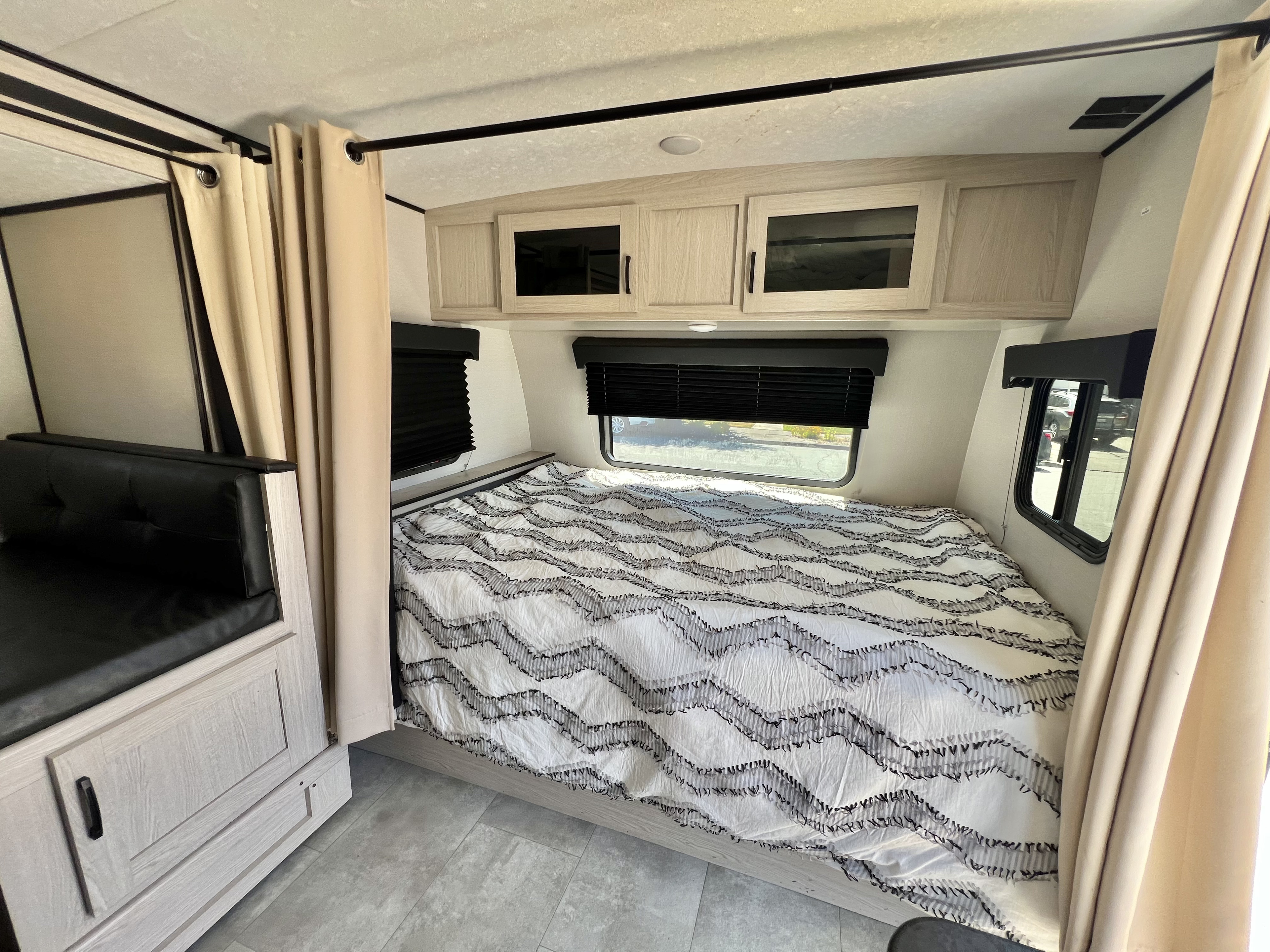 RV rental interior with a comfortable bed, light wood cabinets, and privacy curtains for a cozy stay.. Coachmen Apex Nano 2021