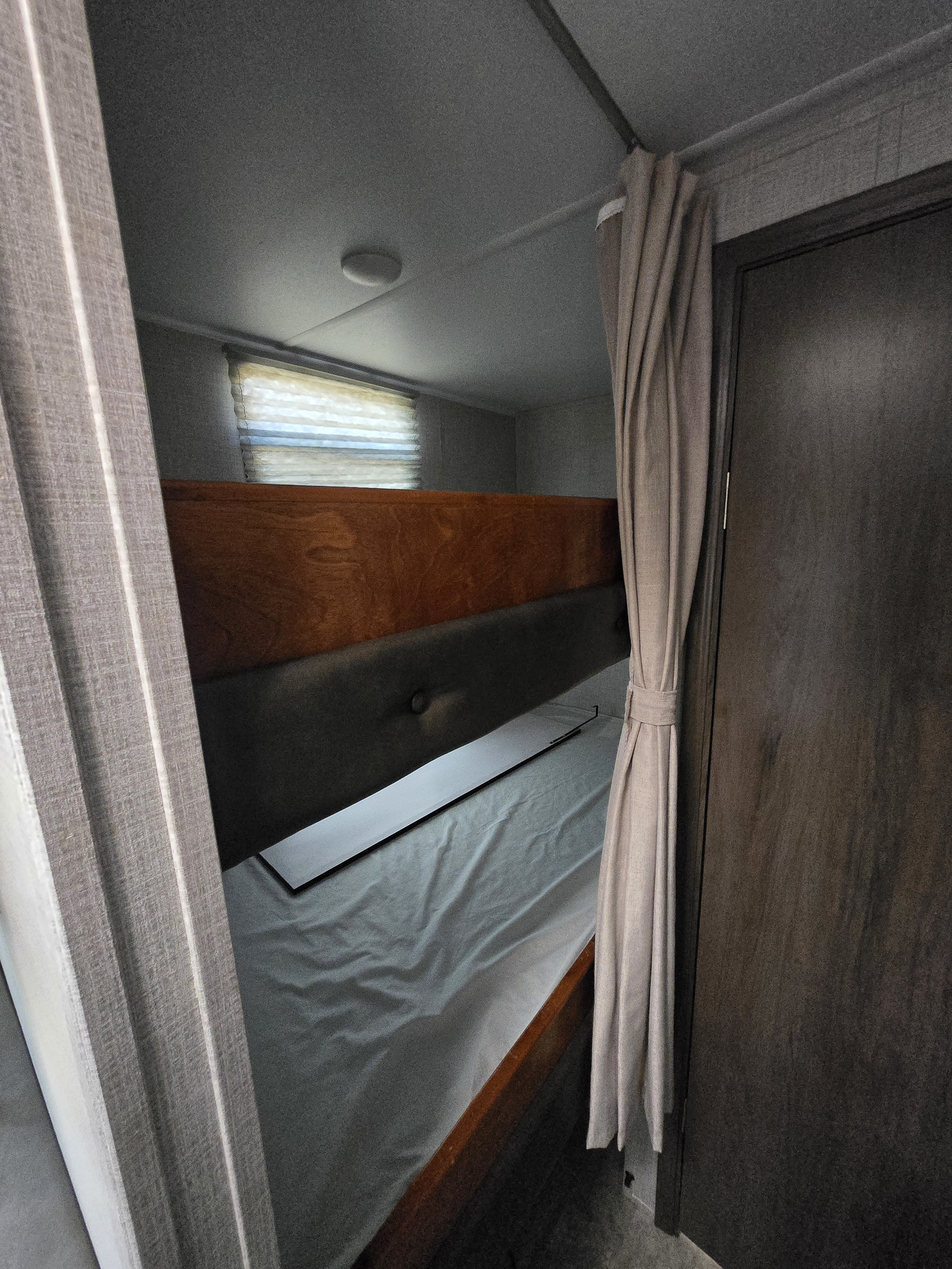 Cozy RV rental interior with bunk beds and window blinds, perfect for travel accommodation.. East to West Della Terra 2021