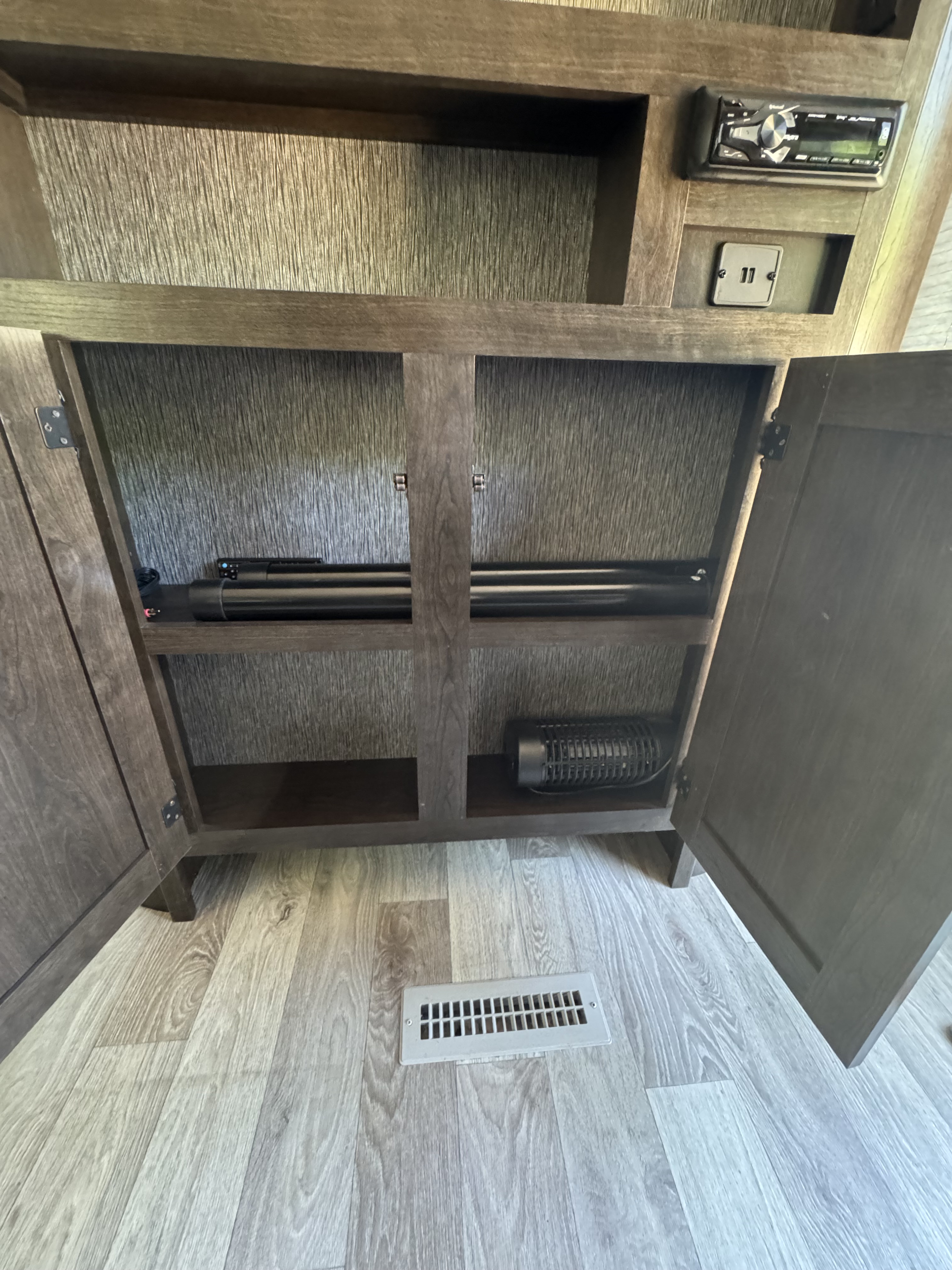 Open storage & entertainment cabinet in an RV rental, featuring a stereo, USB ports, soundbar, and a small fan.. Heartland RVs Pioneer 2021