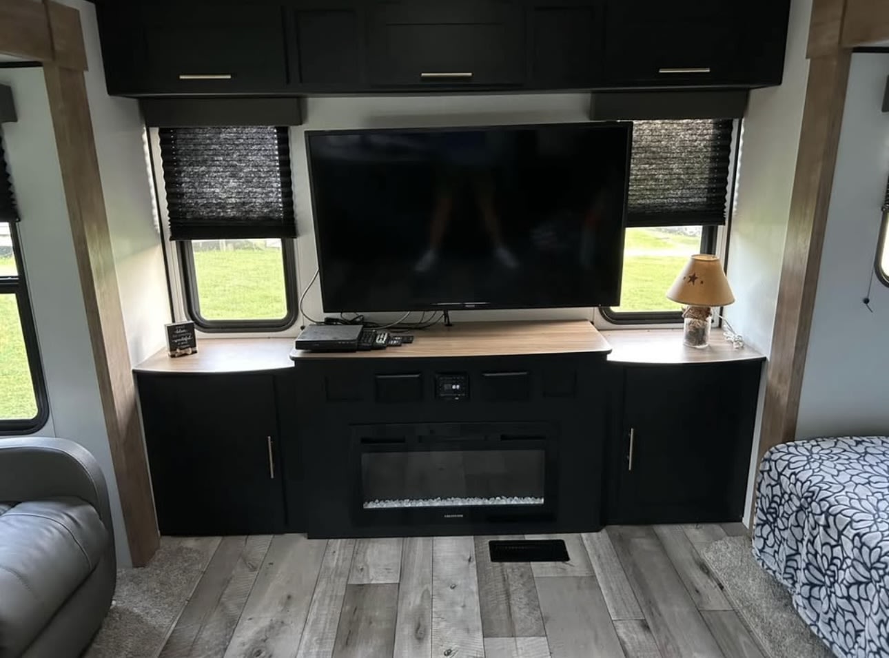 Spacious RV rental interior featuring a modern black entertainment center with TV, electric fireplace, and ample storage.. Keystone RV Springdale 2022